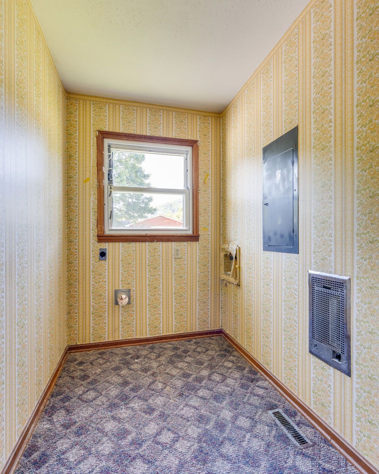 Narrow yellow hallway with a small window, patterned carpet, and wall vents and panels