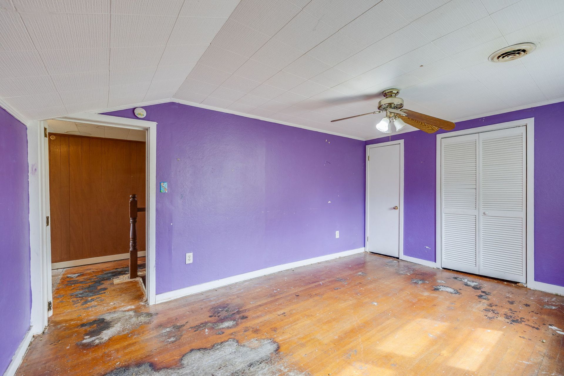 Empty room with purple walls, wood floor, and white closet doors