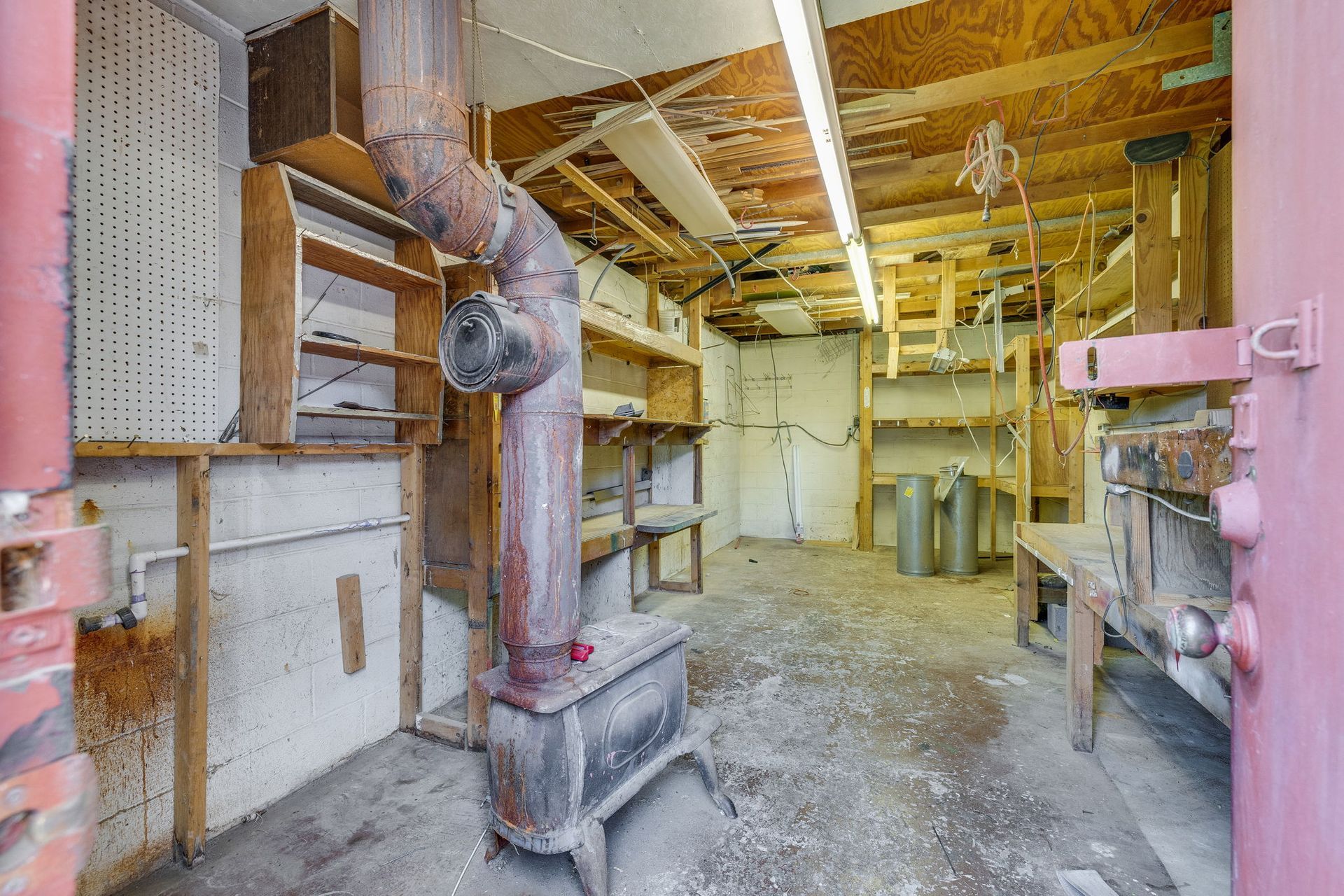 Basement utility room with exposed pipes, furnace, shelves, and unfinished wooden ceiling.