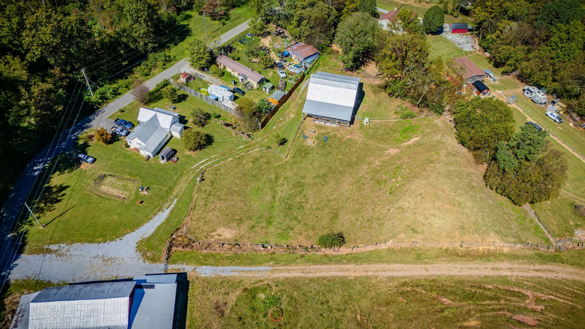 Aerial view of rural homestead with several houses, sheds, a grassy yard, and surrounding trees