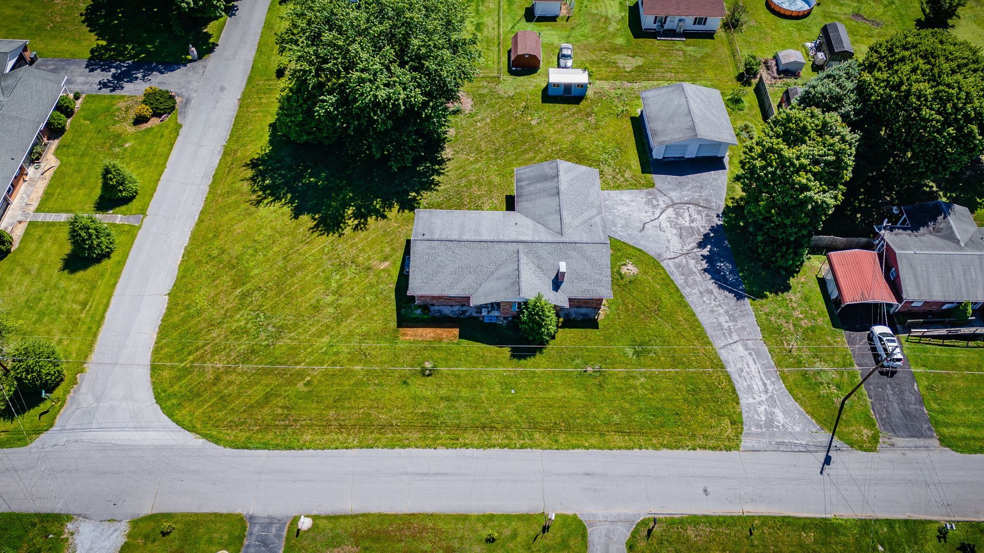 Aerial view of a suburban neighborhood with houses, lawns, driveways, and intersecting streets.