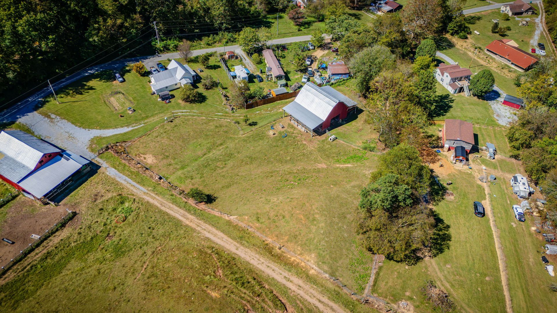 Aerial view of a rural property with houses, barns, dirt roads, and green fields.