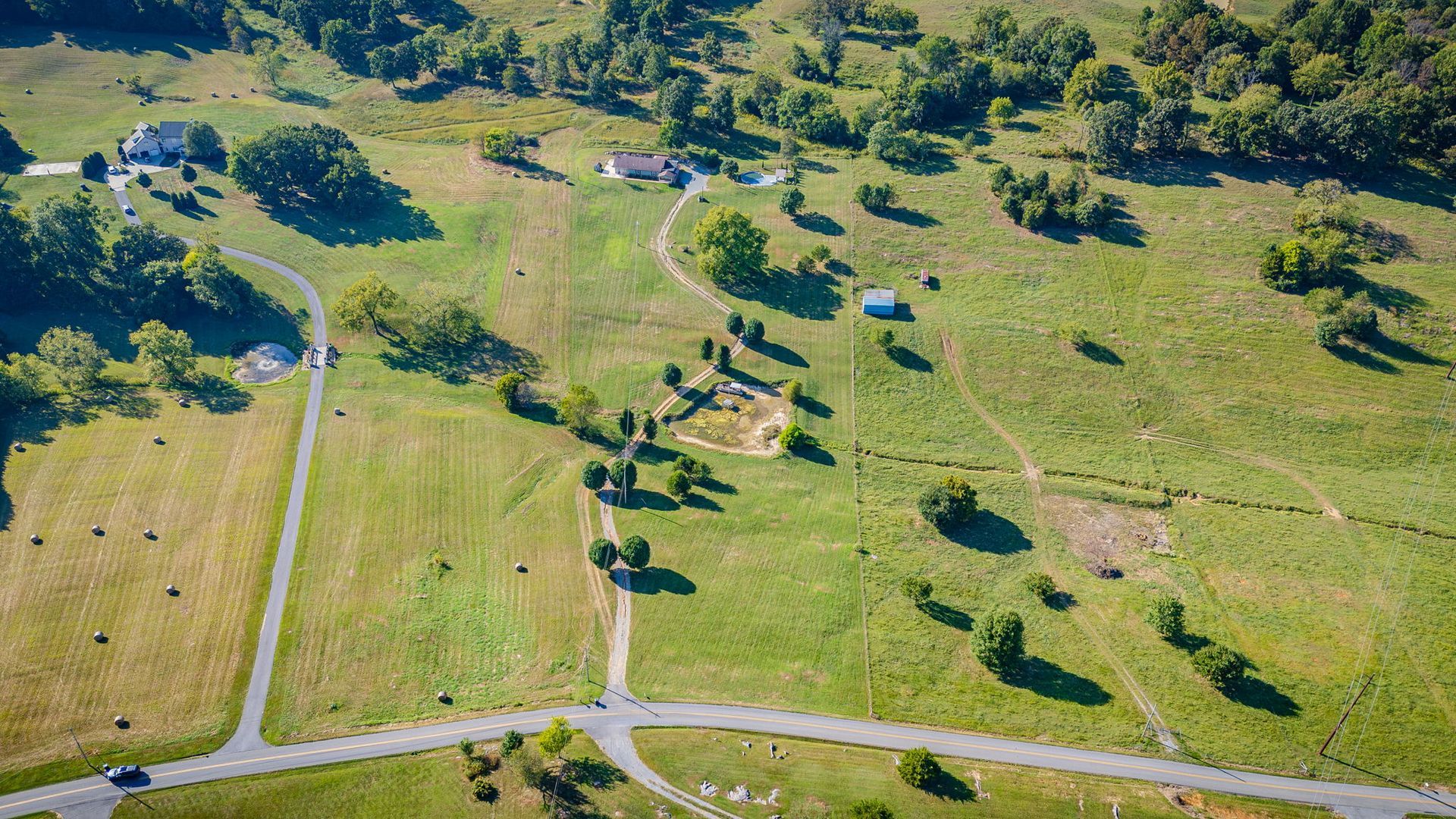 Aerial view of a green park with winding paths, scattered trees, and open grassy fields.