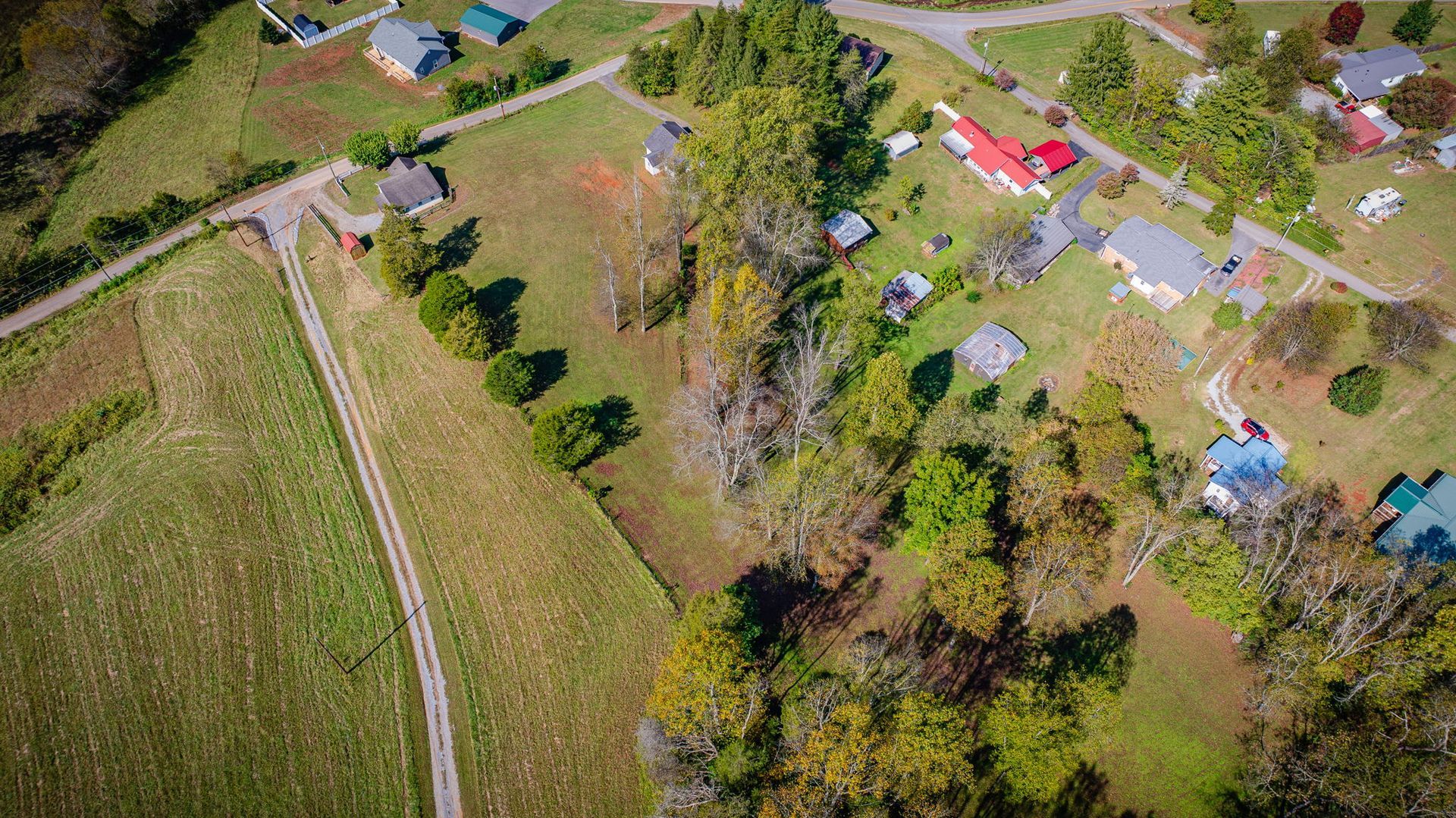 Aerial view of a rural property with fields, trees, and several colorful houses and tents.