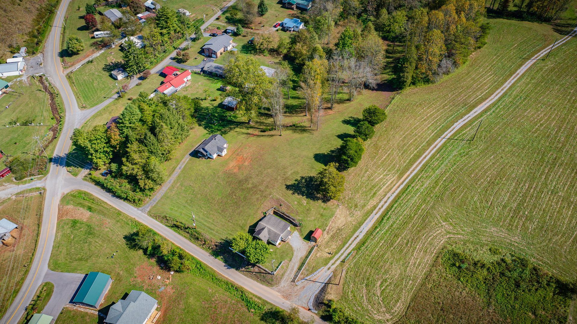 Aerial view of rural homes, roads, and green fields on a sunny day.