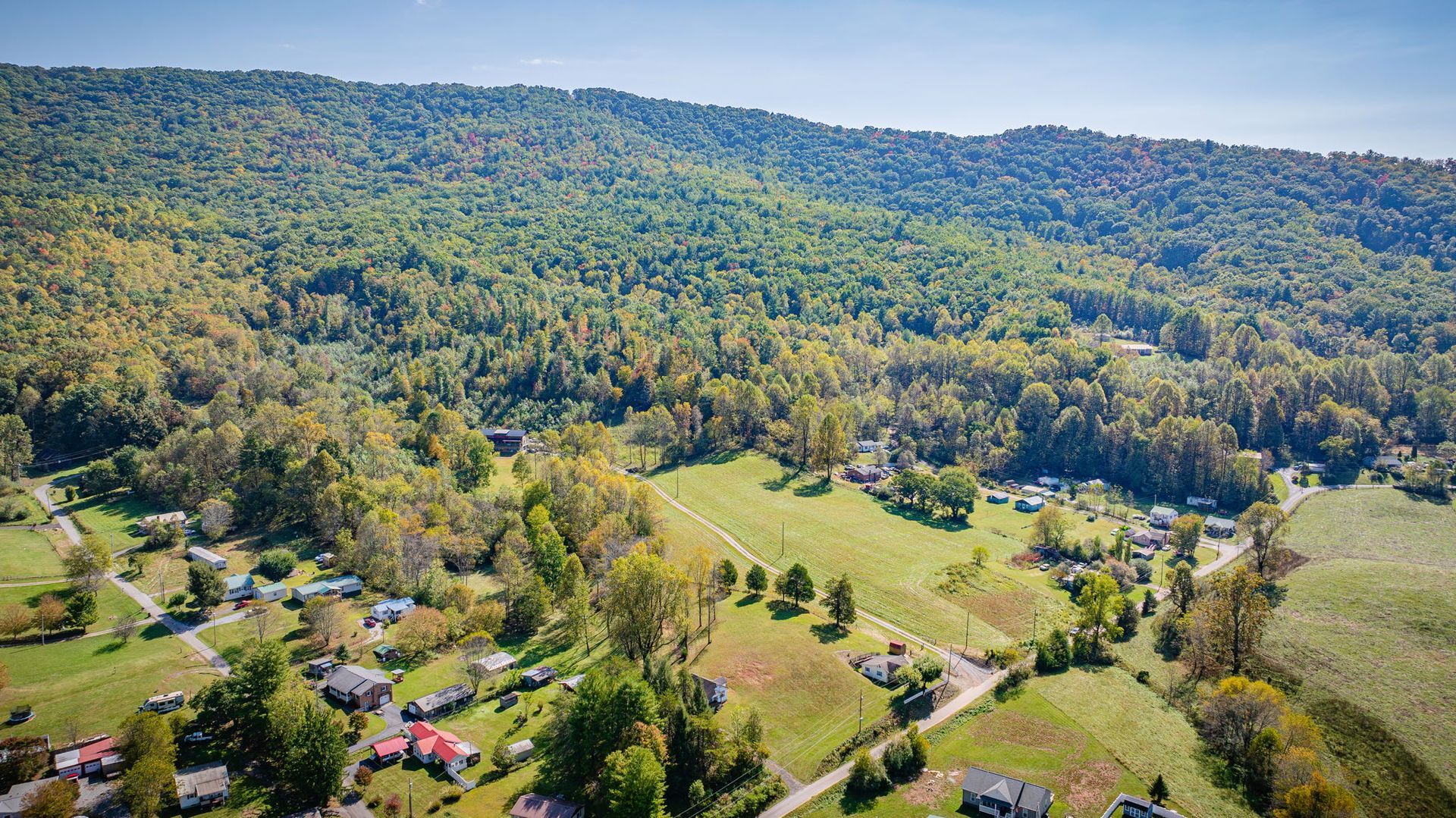 Aerial view of a green valley with scattered homes, trees, and wooded hills
