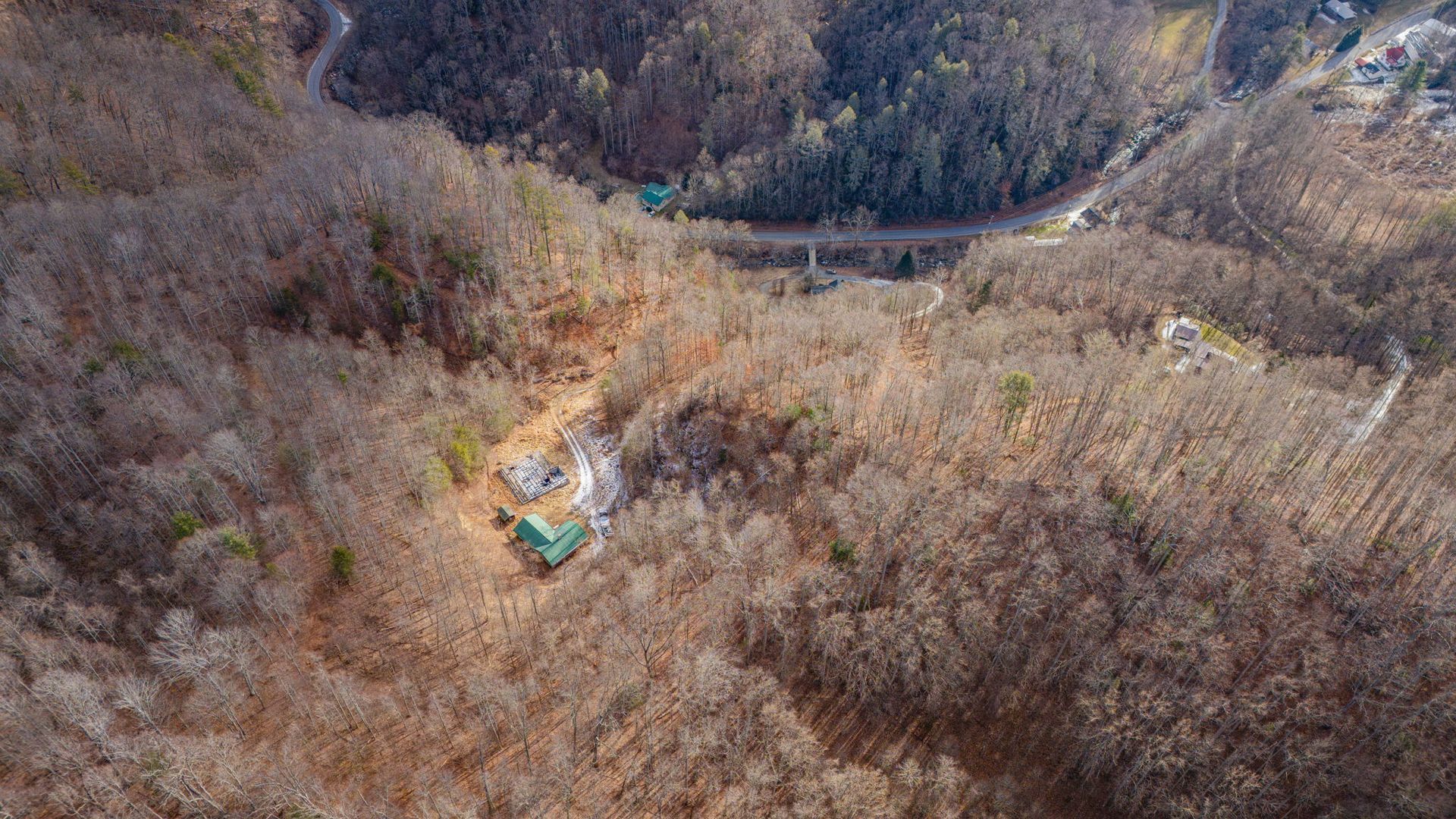 Aerial view of a mountain with a road winding through it and a few buildings nestled in the trees.
