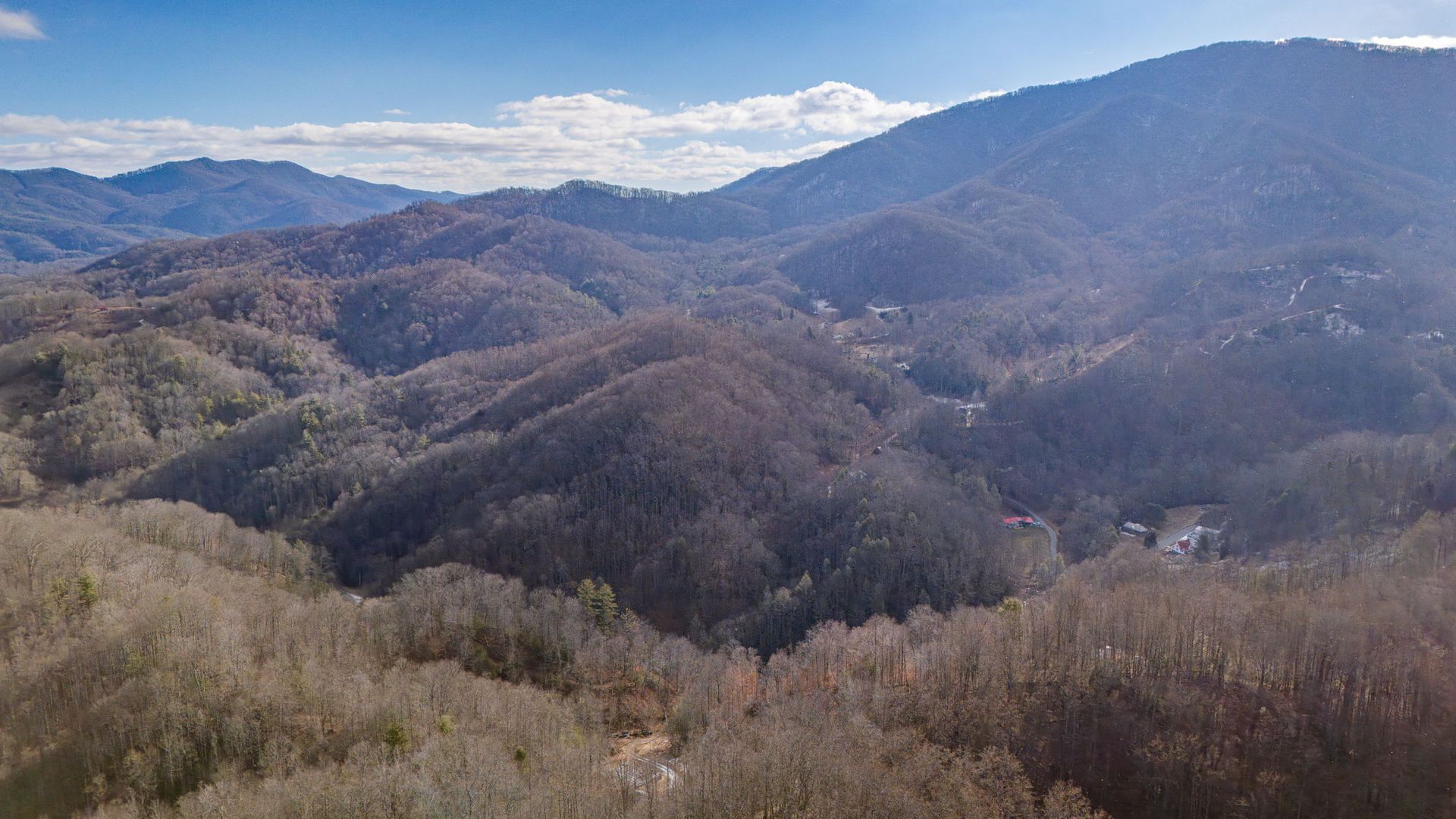 Mountainous landscape with brown trees and blue sky.