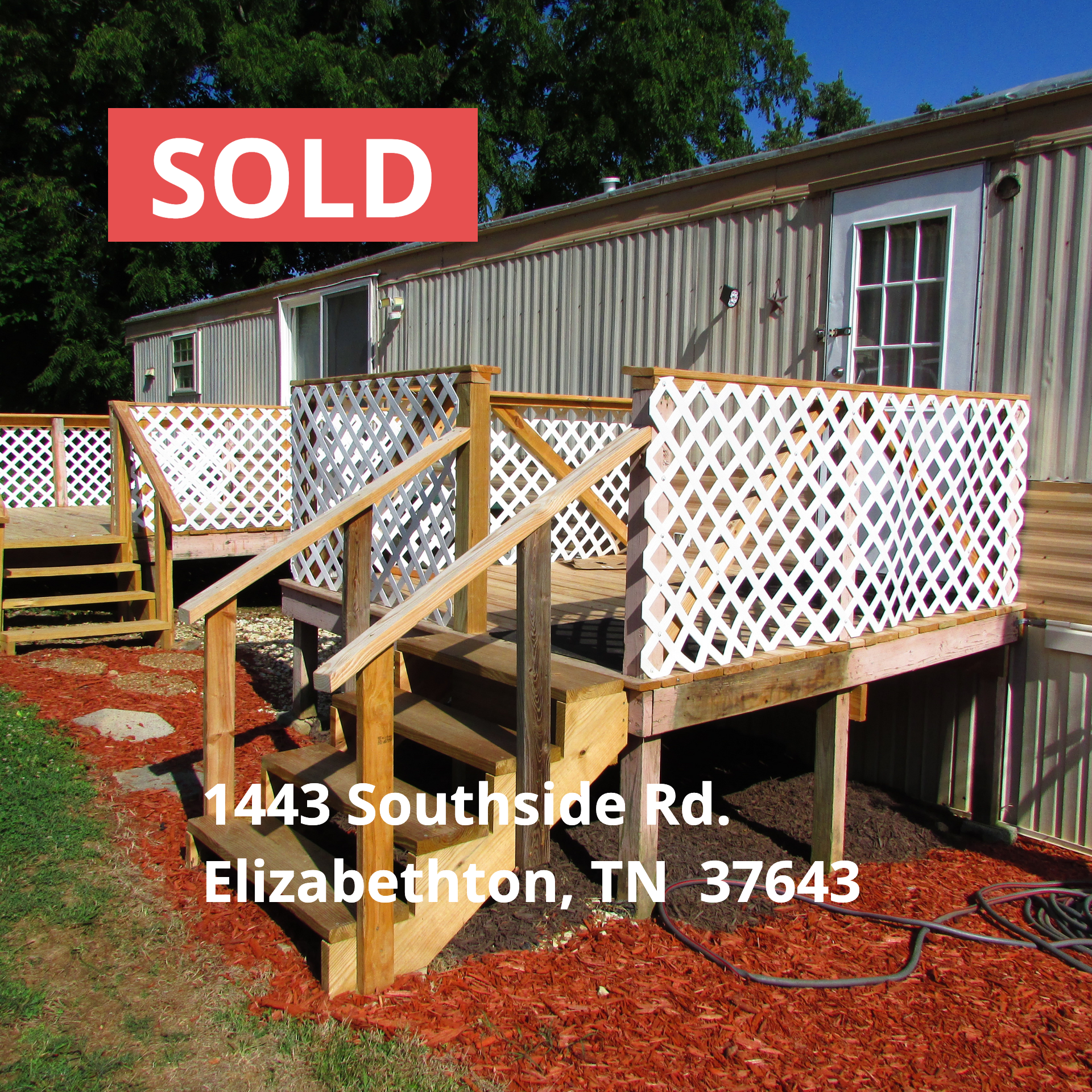 A mobile home with a wooden deck and stairs sold at auction by Collins & Co. 