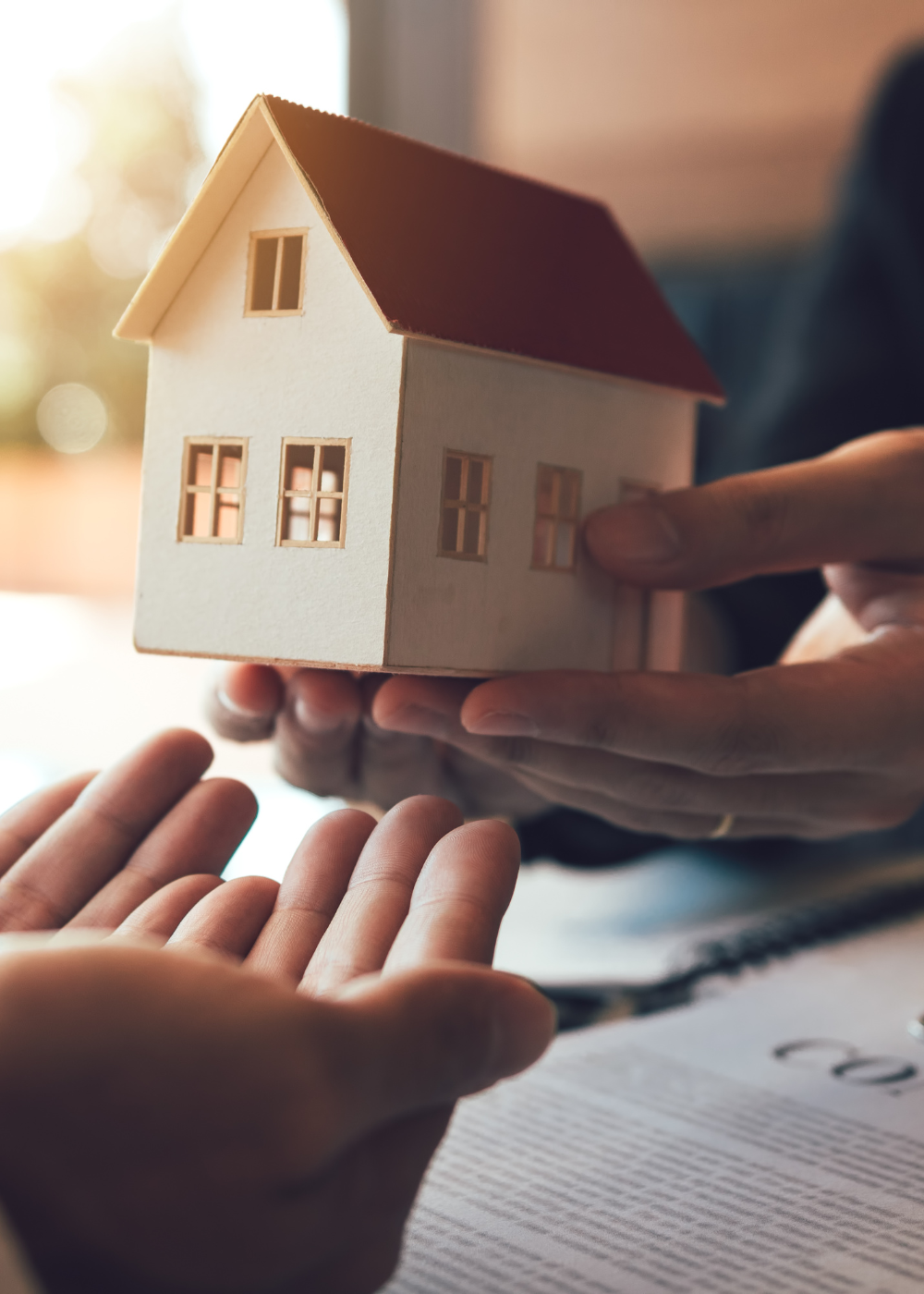 Two hands giving a miniature house to a another set of hands that are accepting it like a prayer sacrament
