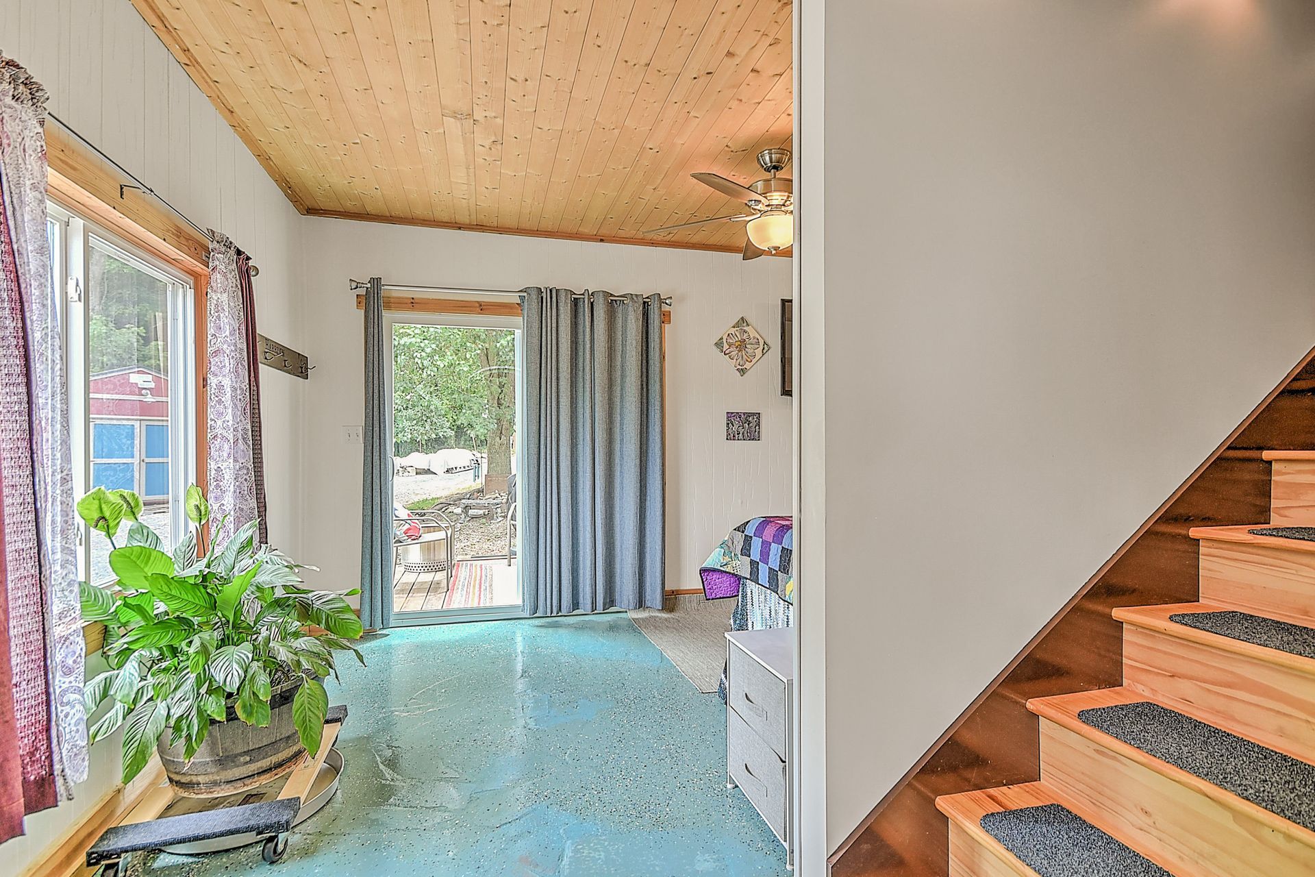 Bright entryway with plants, sheer curtains, and a wooden staircase on the right.
