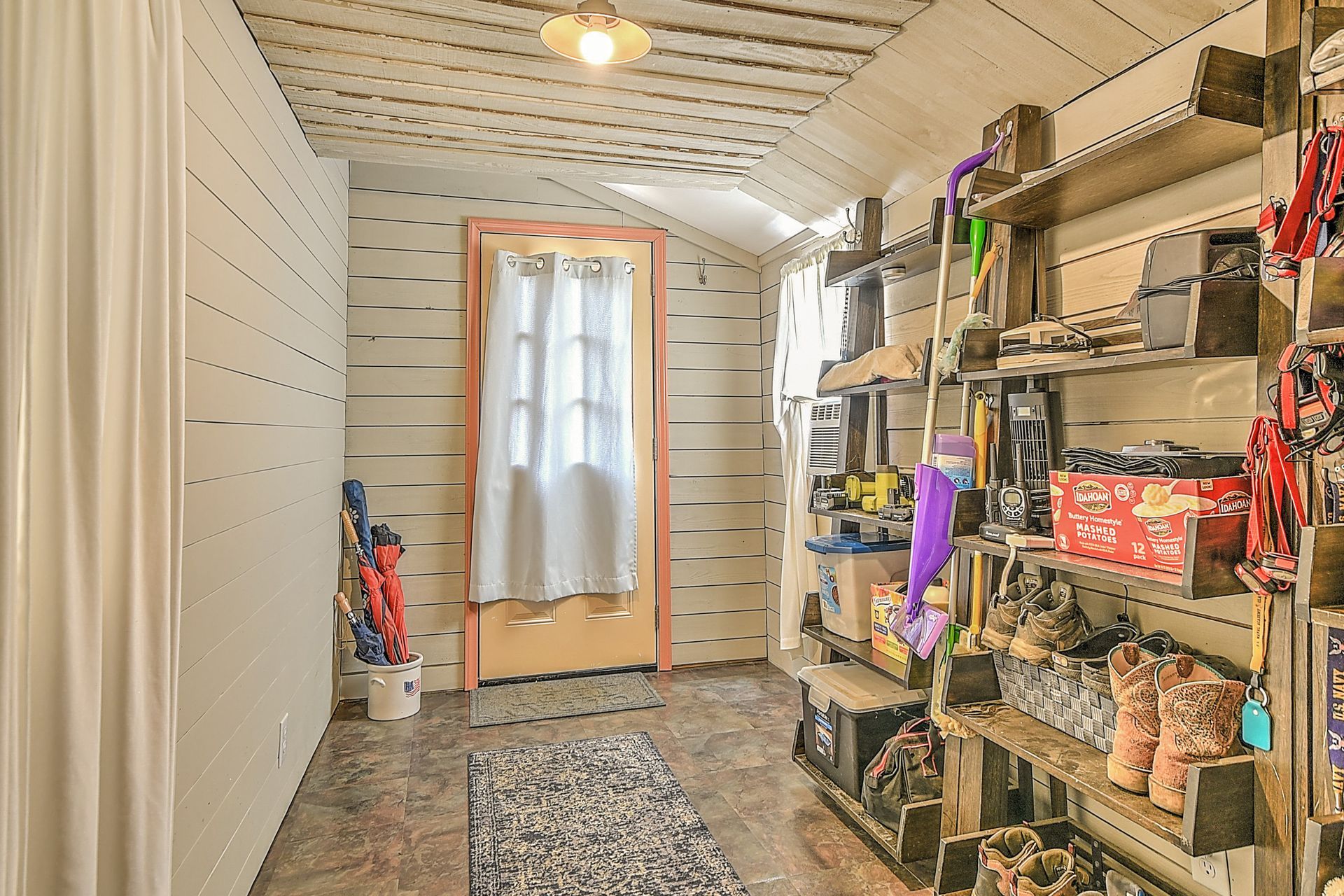 Narrow white storage room with shelves of supplies and a door at the far end