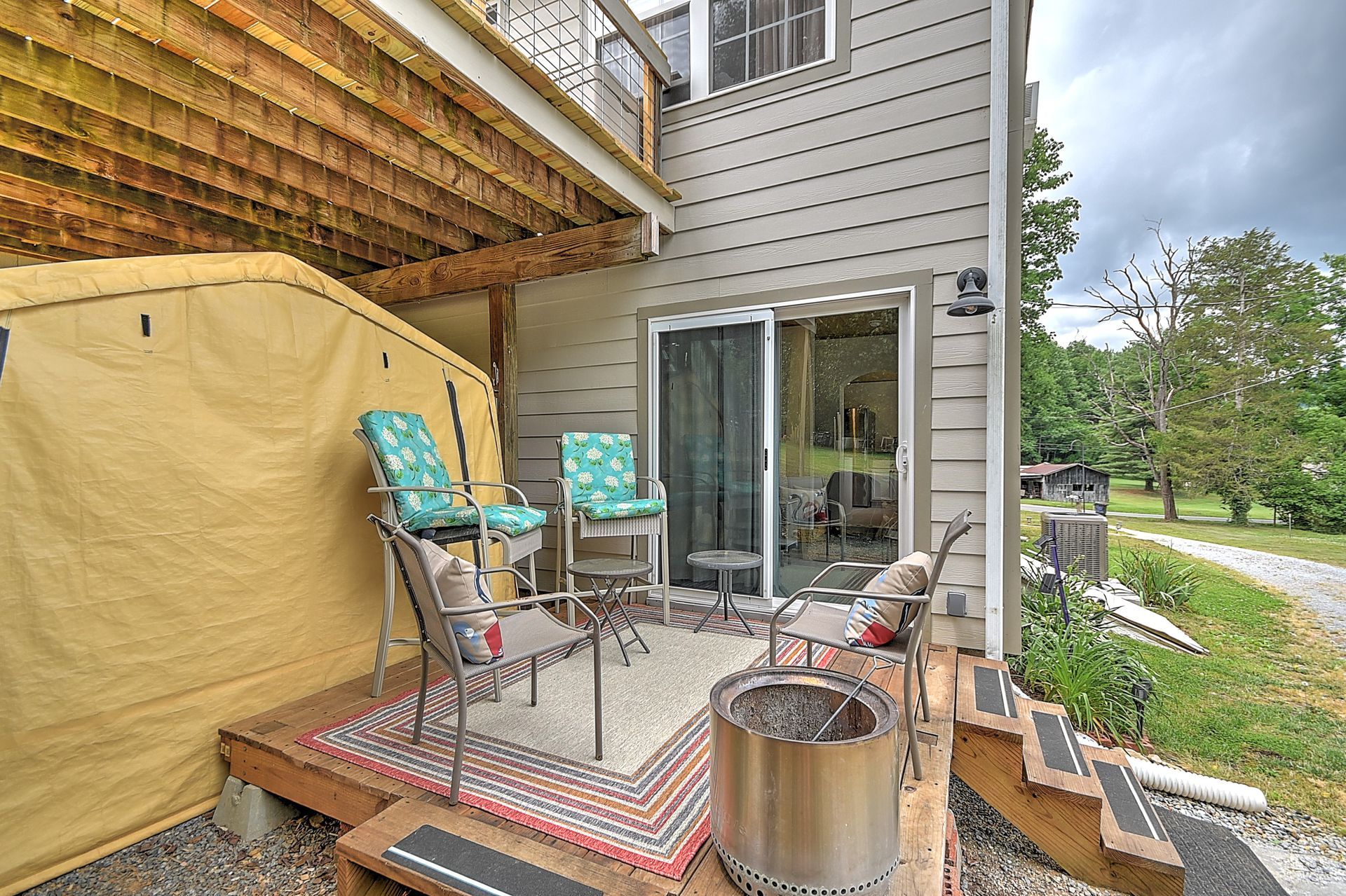 Patio with table, chairs, grill, hot tub, and sliding glass door beside a house