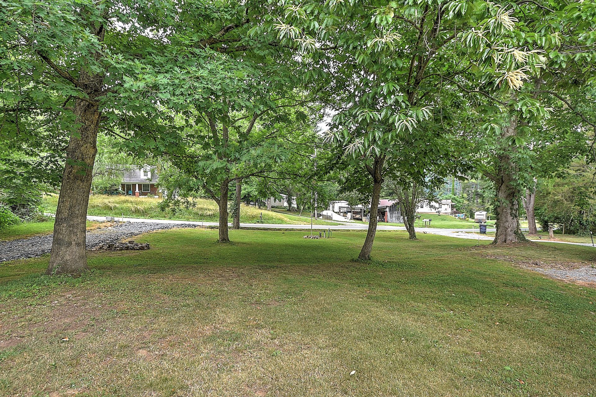 Tree-filled grassy park with a few houses in the background