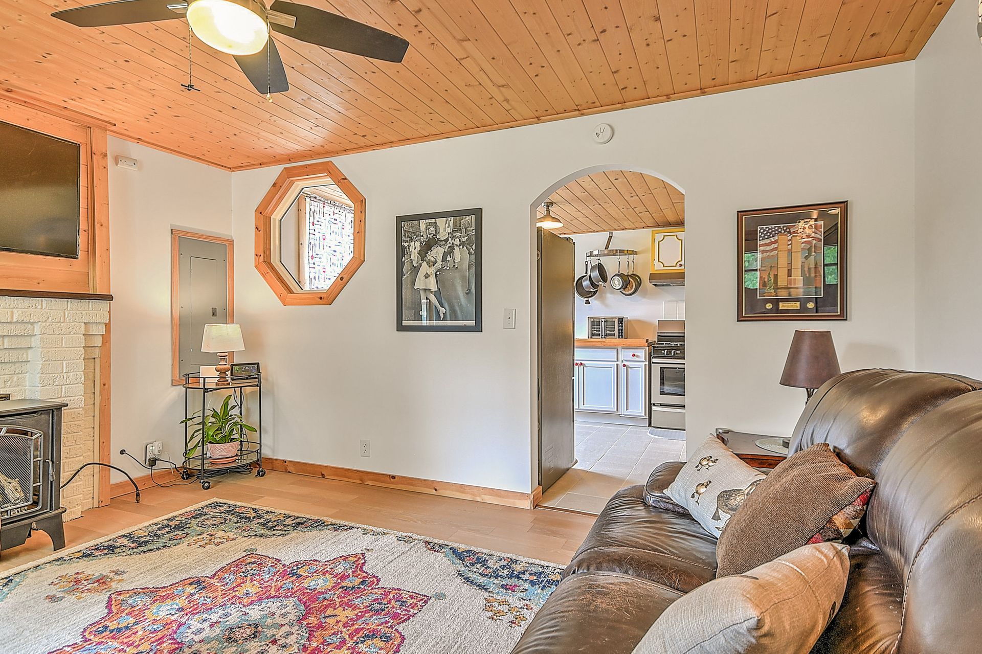 Cozy living room with sofa, rug, fireplace, and arched doorway to a kitchen