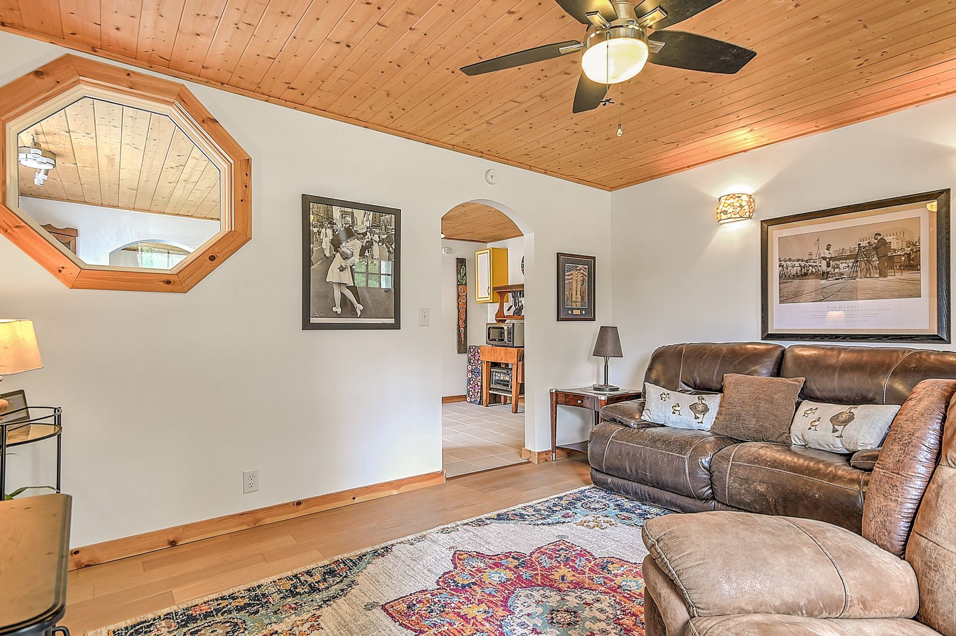 Cozy living room with beige sectional sofa, wood ceiling, ceiling fan, framed art, and patterned rug