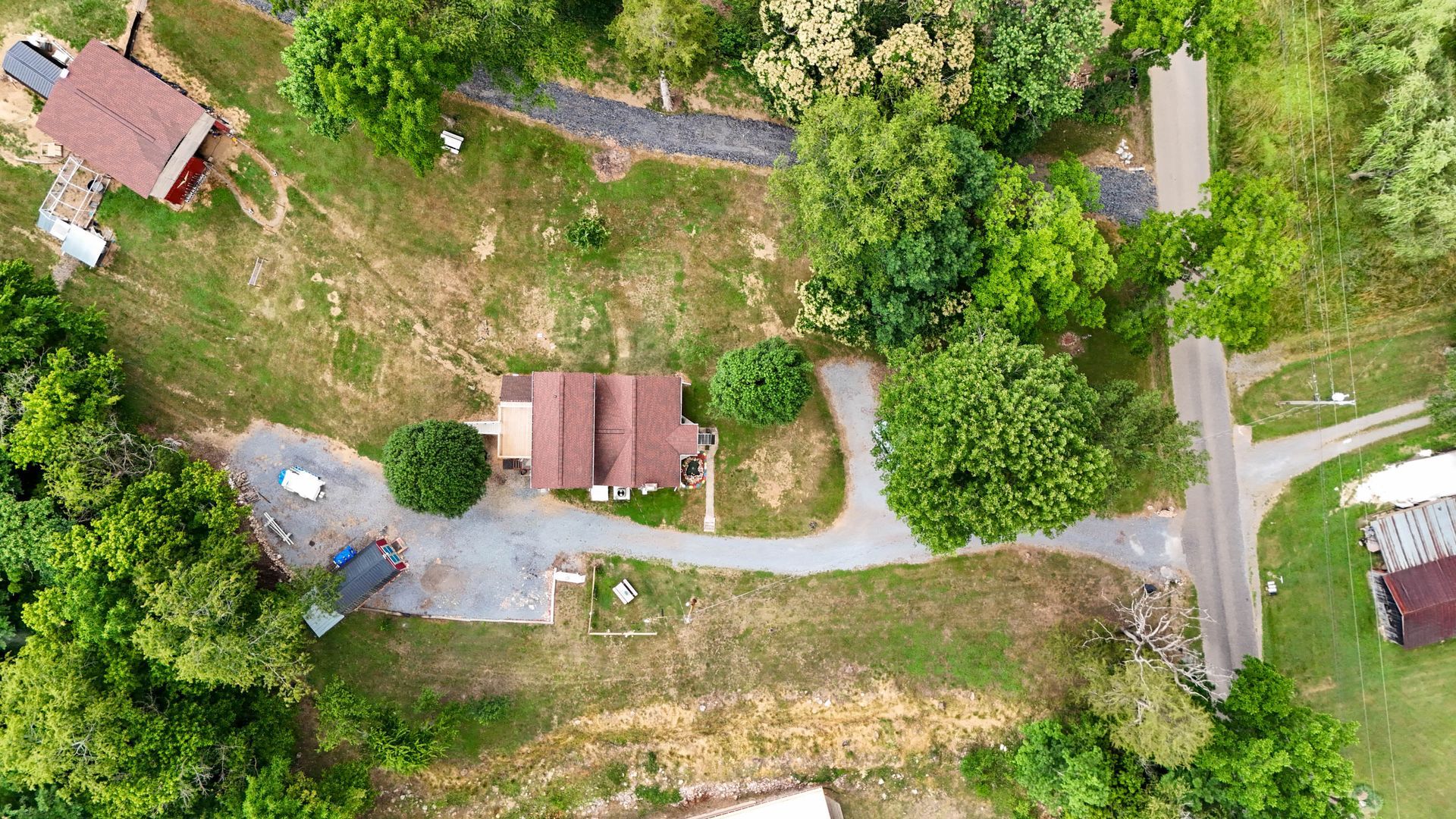 Aerial view of a rural property with several small houses, a winding driveway, and trees
