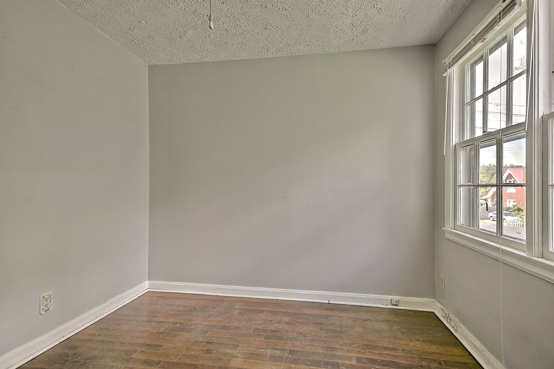 Empty gray room with hardwood floor and large windows on the right side