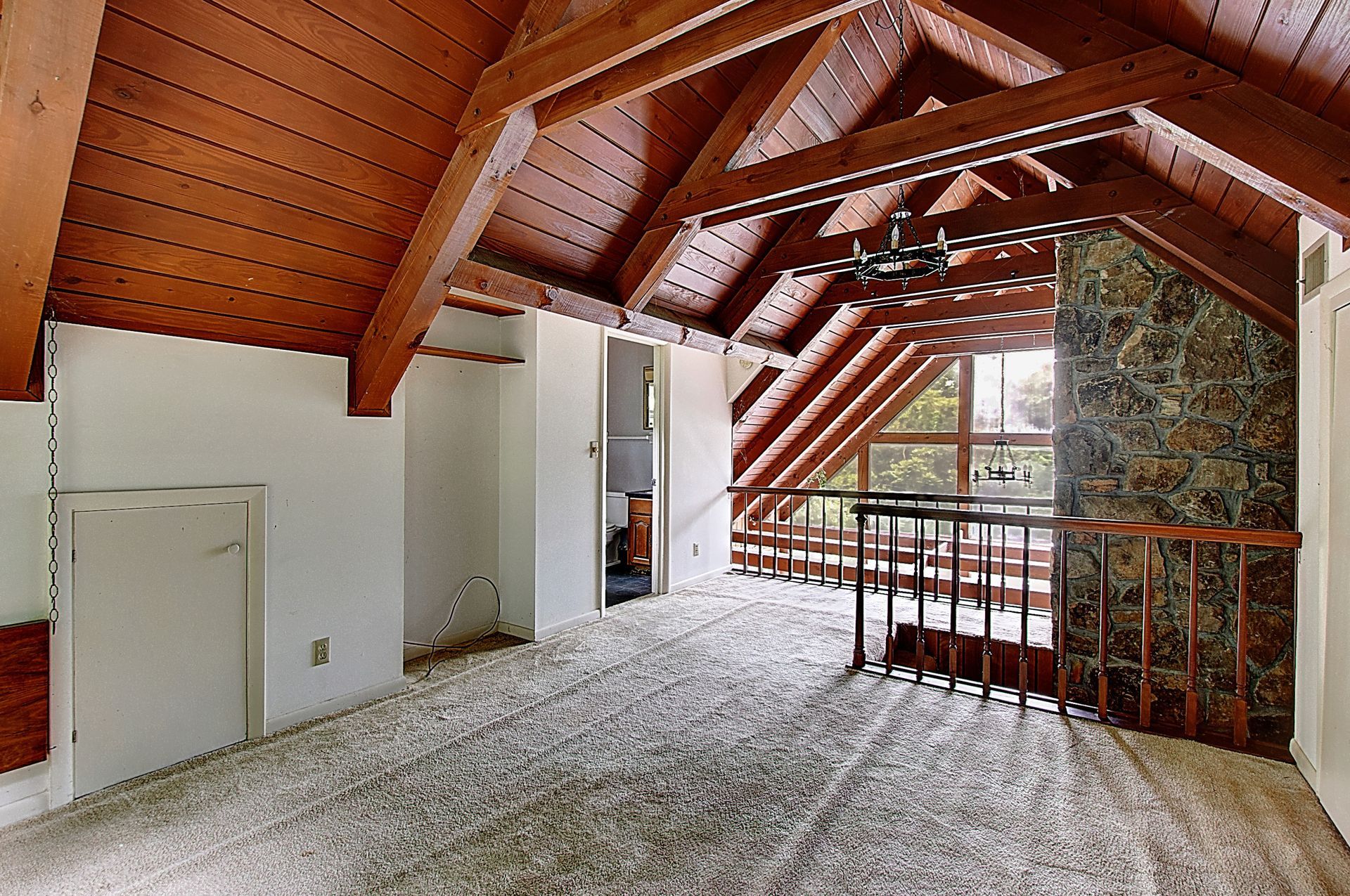 An attic with wooden beams and a stone fireplace