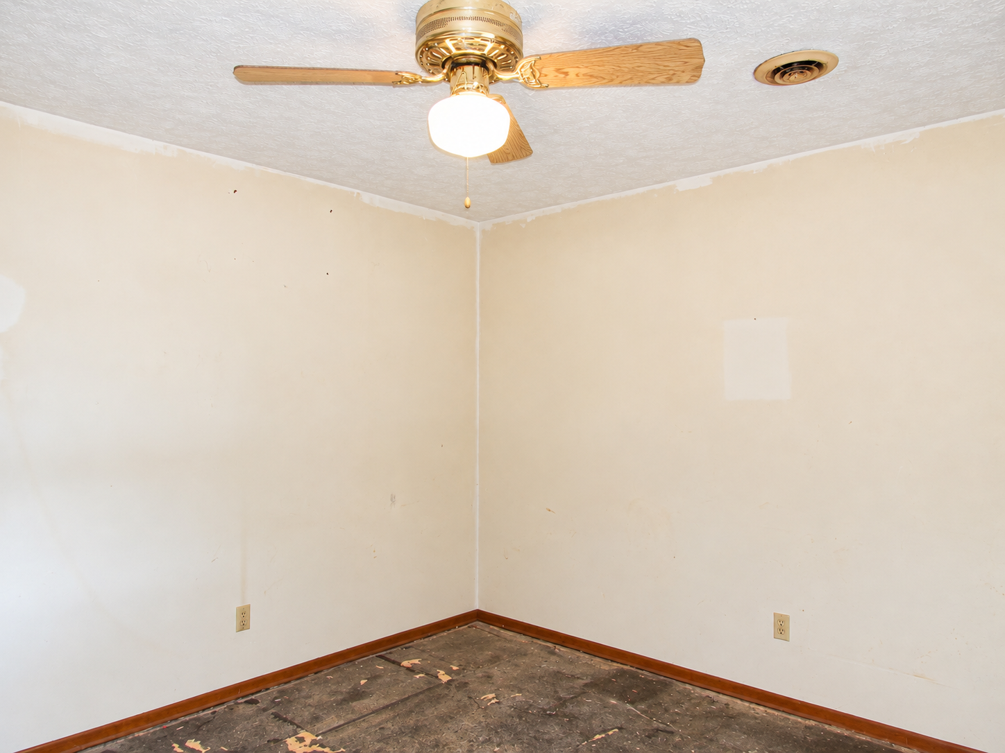 Empty beige room with ceiling fan, white ceiling, and worn carpet