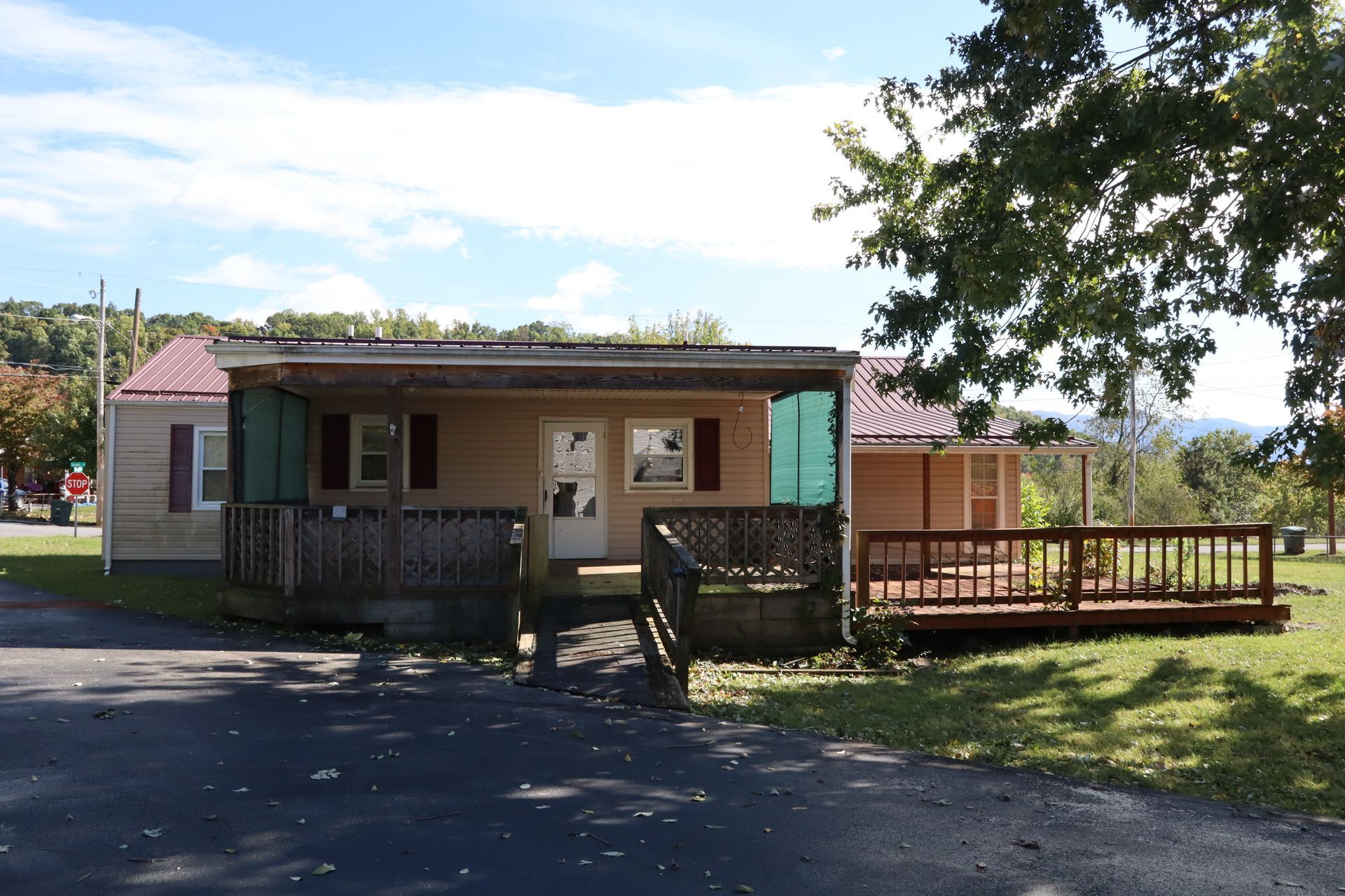 Small house with a porch and wooden deck in a sunny rural setting