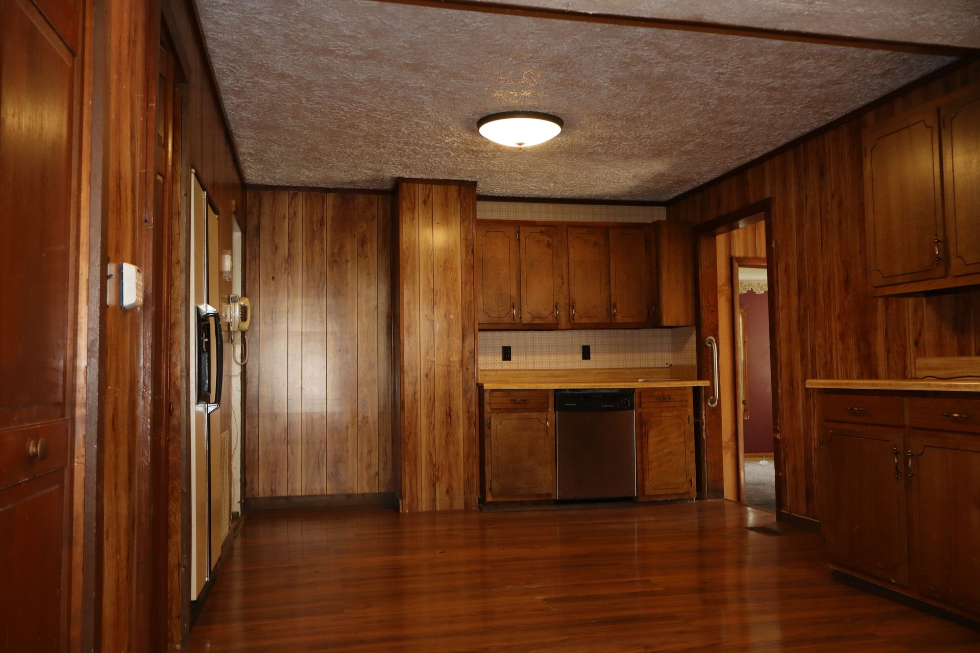 Wood-paneled room with hardwood floor, built-in cabinets, and a doorway on the right.