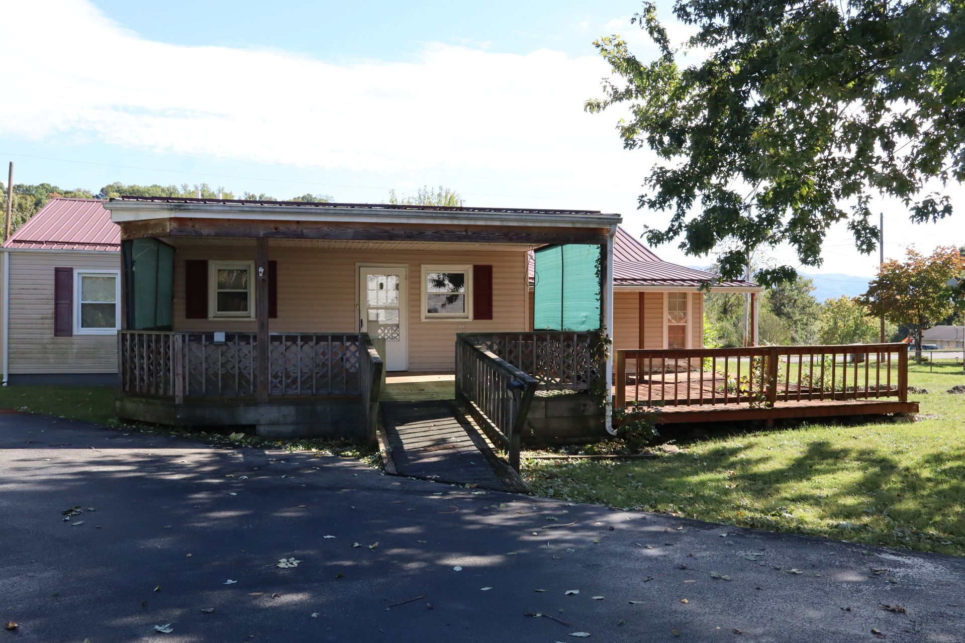 Small single-story cabin with a wheelchair ramp and wooden porch in a grassy yard under a clear sky