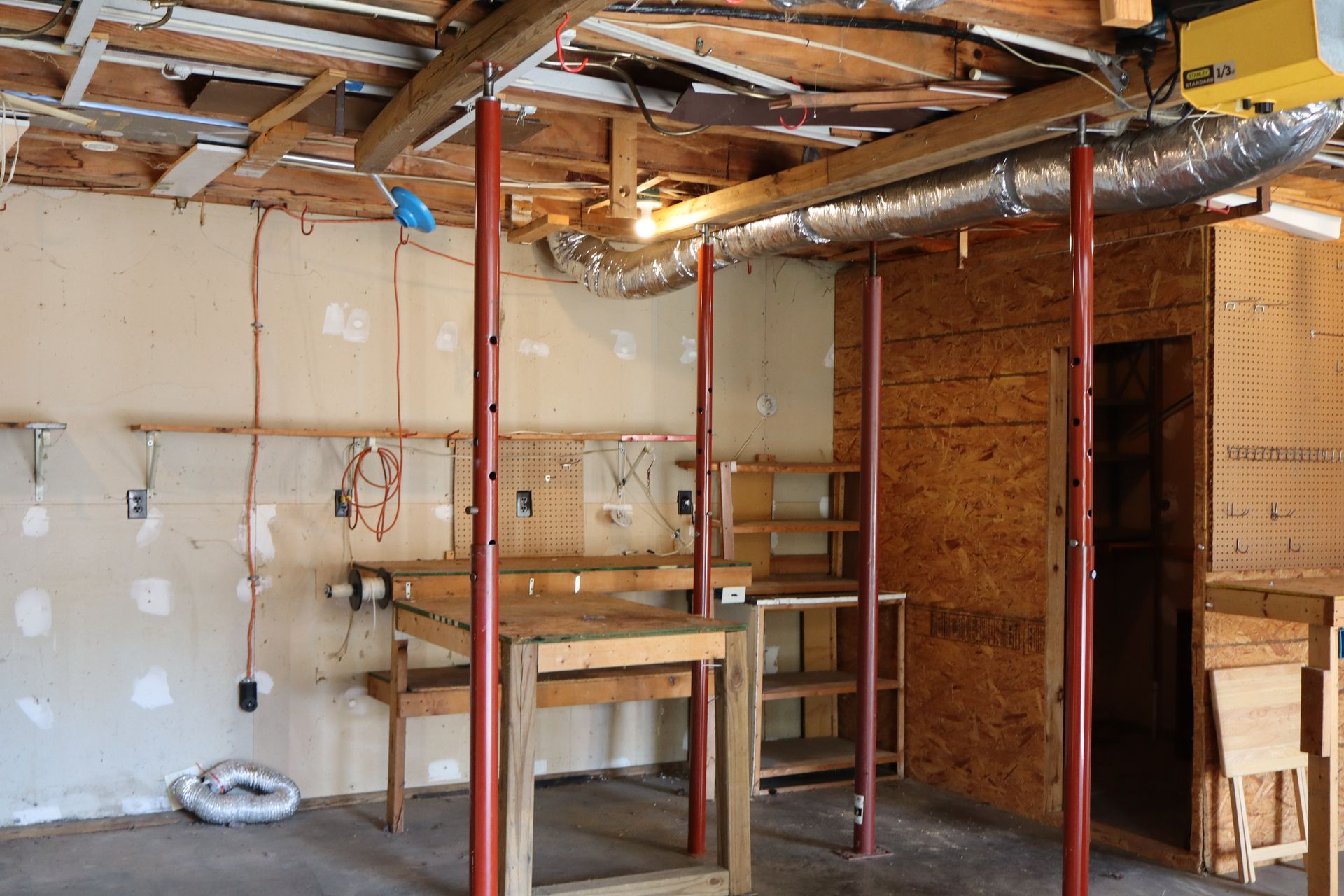 Unfinished basement with exposed studs, beams, ductwork, and a workbench against the wall.