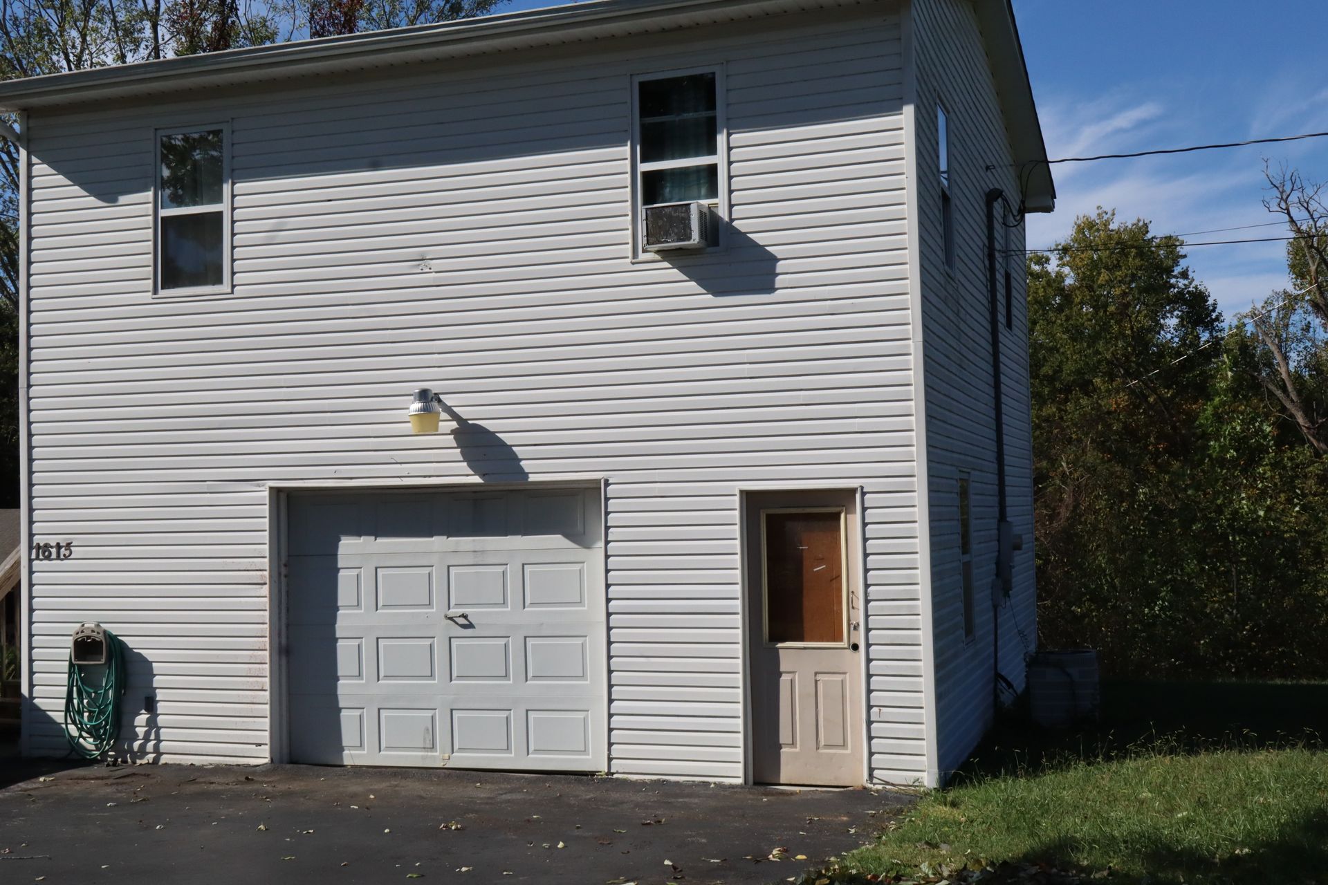 White house exterior with garage door and side entry door, viewed from the driveway.