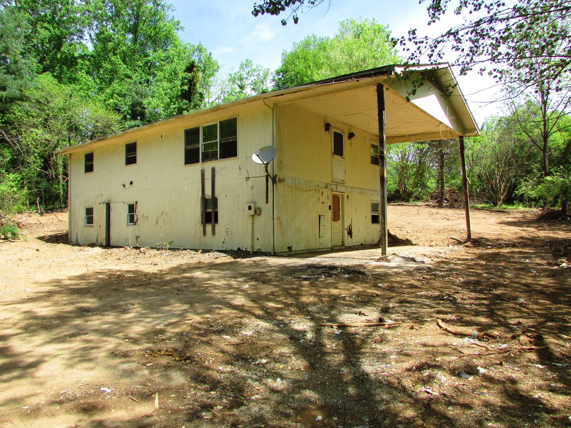 Small yellow house with a metal roof in a wooded, dry clearing