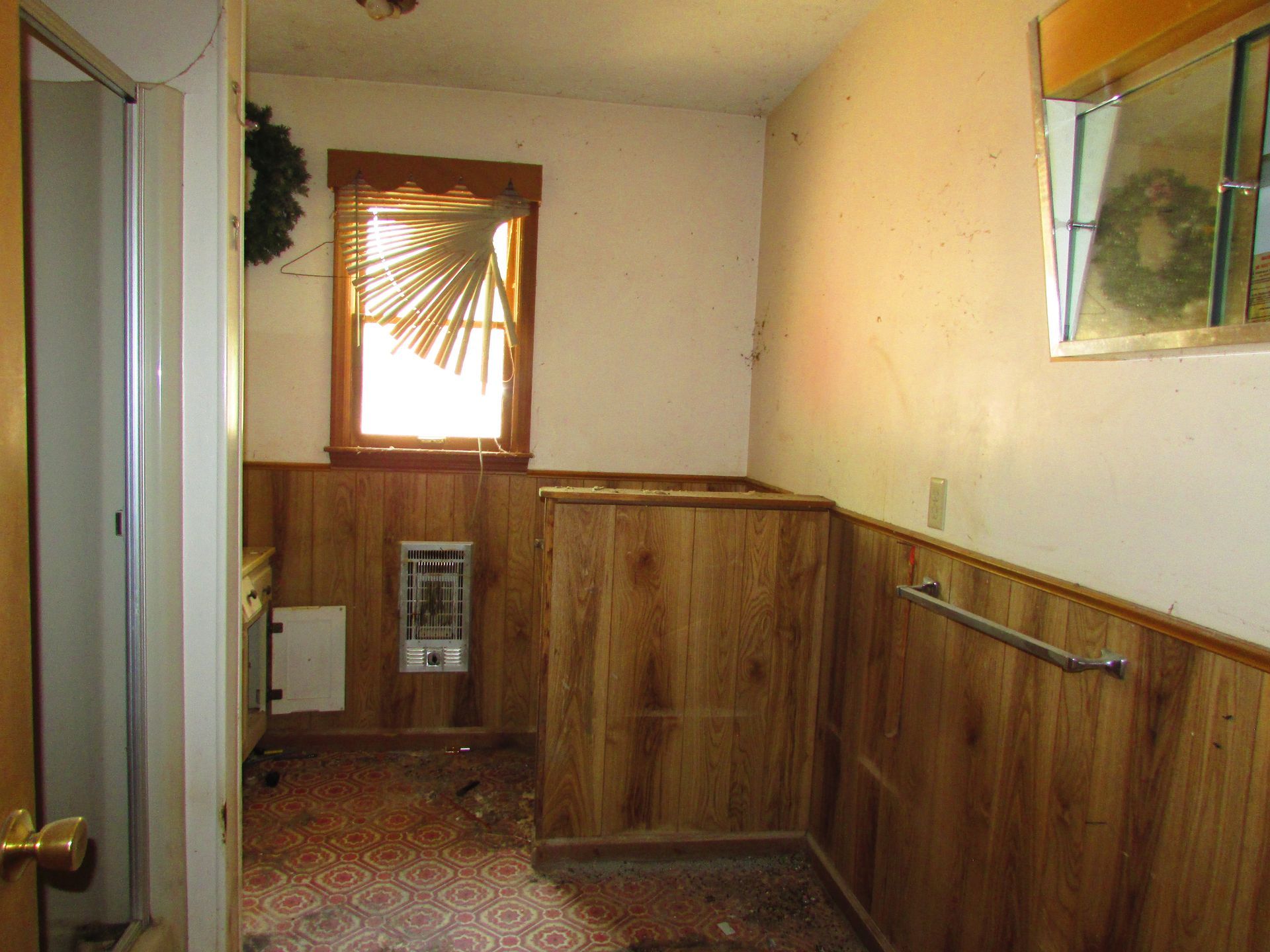Small wood-paneled bathroom with a window, sink cabinet, and mirrored medicine cabinet.