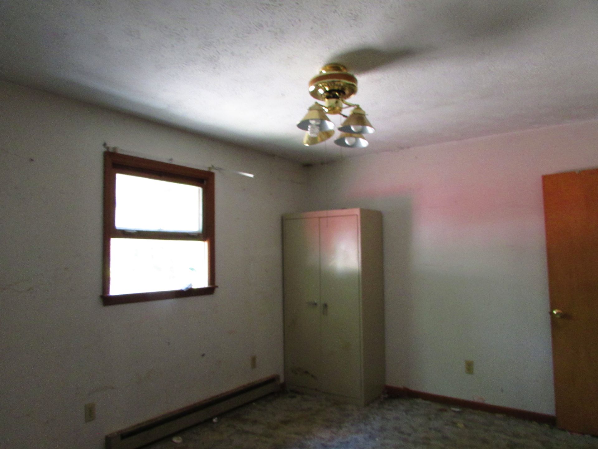 Empty bedroom with white walls, window, ceiling fan, and closet.