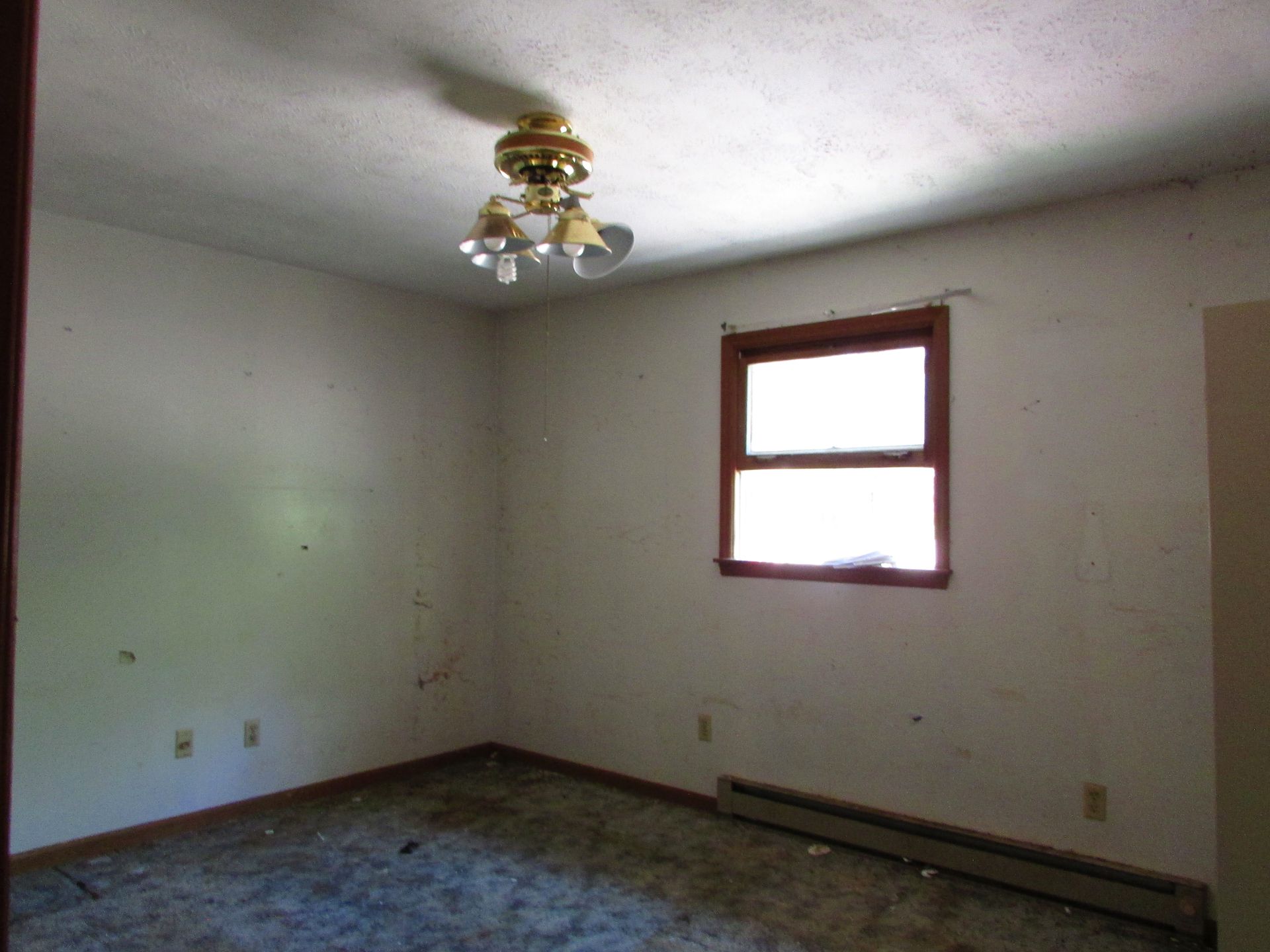 Empty beige room with a small window, ceiling fan, and bare floor