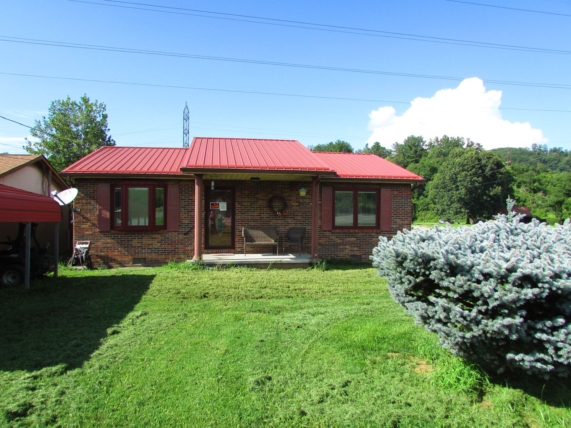 Brick house with red roof and green lawn under a blue sky