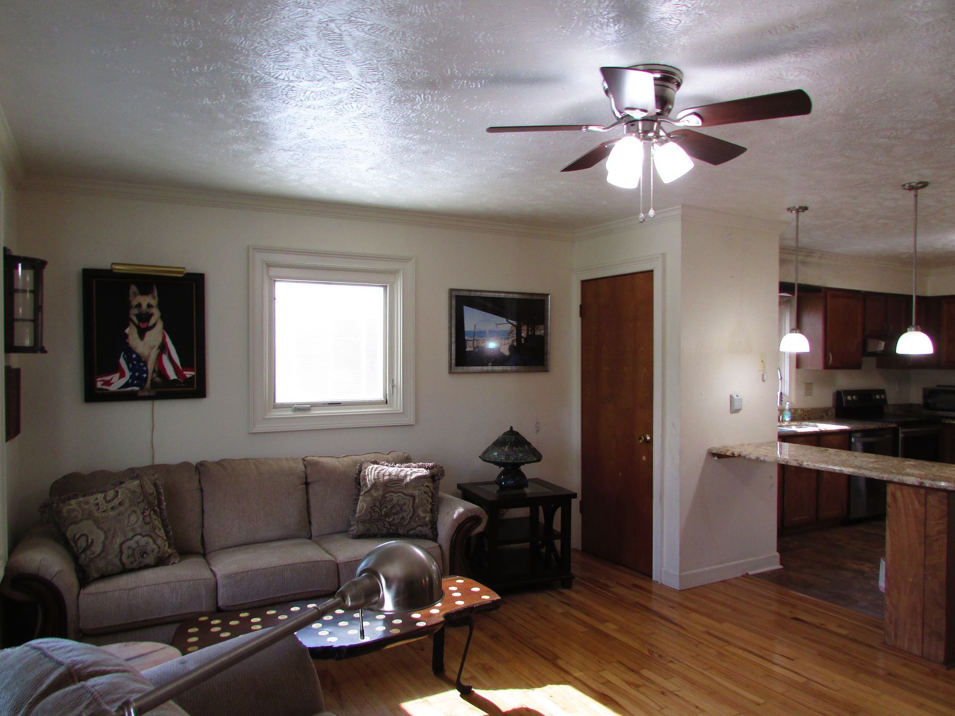 Living room with gray sofa, coffee table, ceiling fan, and open view to kitchen and dining area