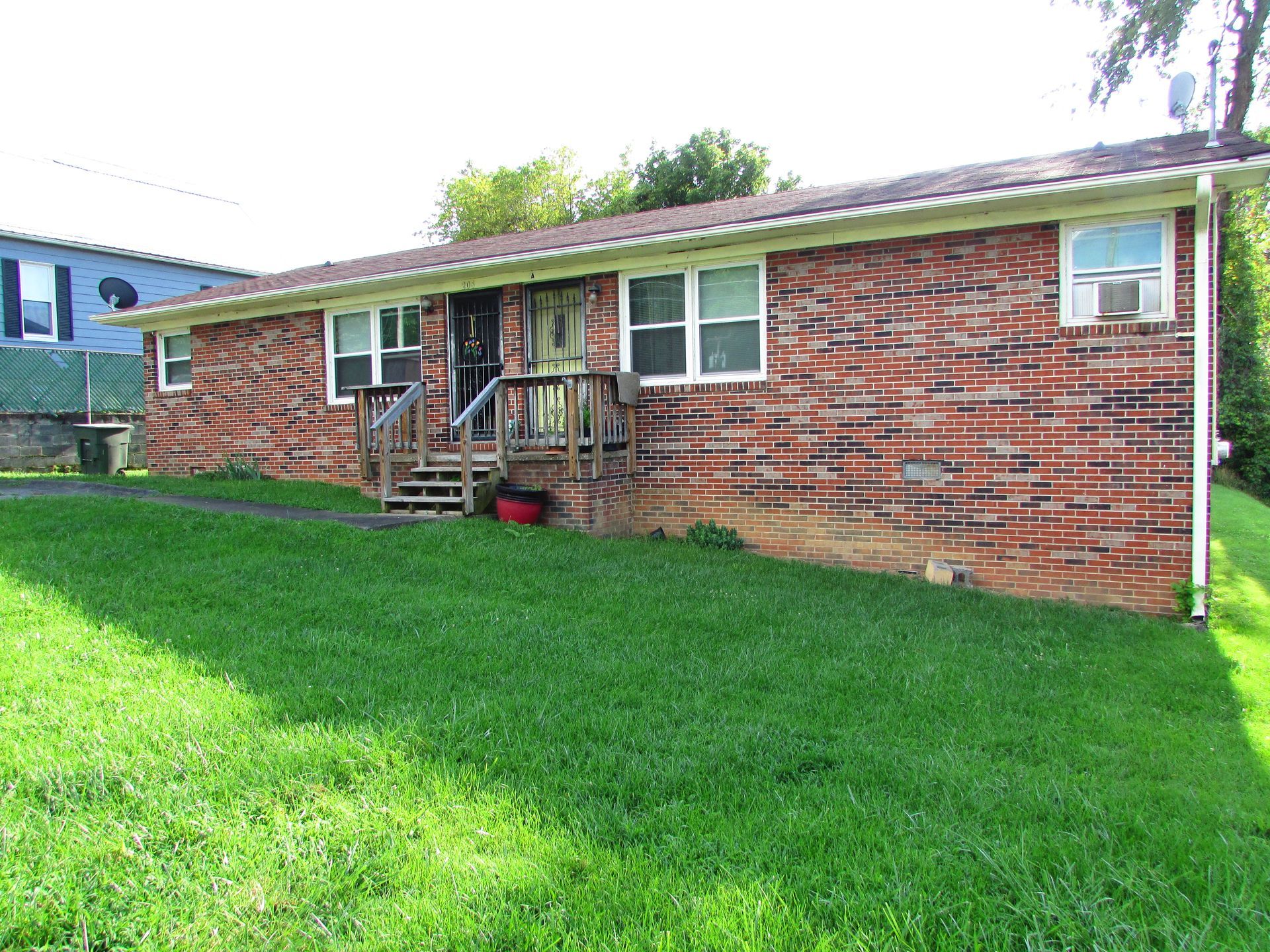 Brick house with green lawn, white-trimmed windows, and a small front stoop.