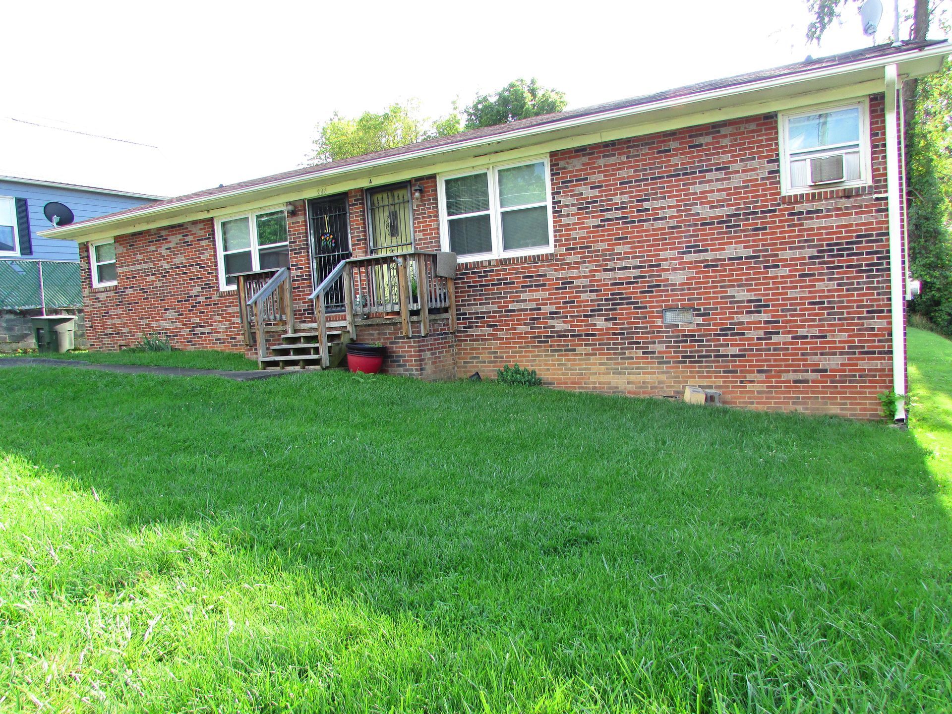 Brick house with a small porch and large green lawn on a sunny day