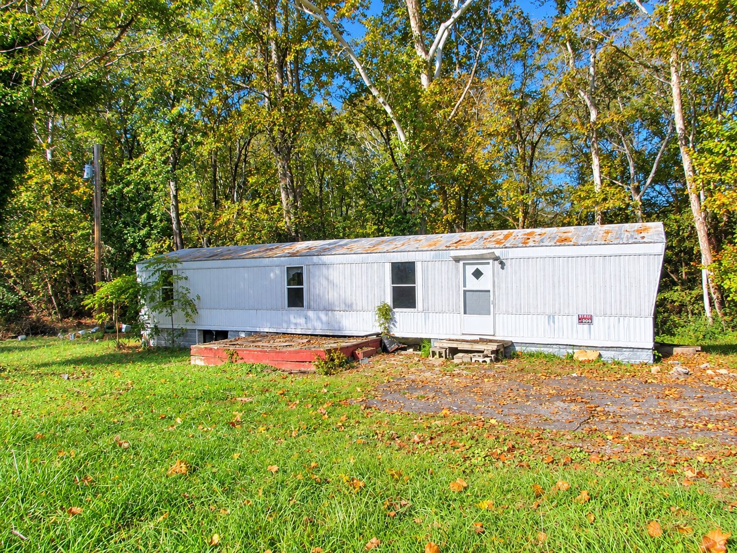 White mobile home in a grassy yard with trees in the background