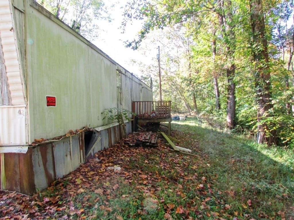 Mobile home beside a wooded path with autumn leaves and a small porch
