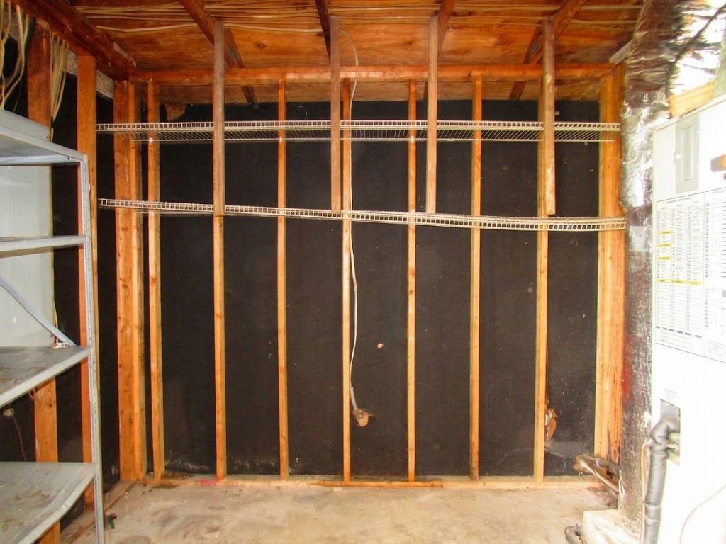 Partially framed wall with orange studs and black sheathing inside a construction site
