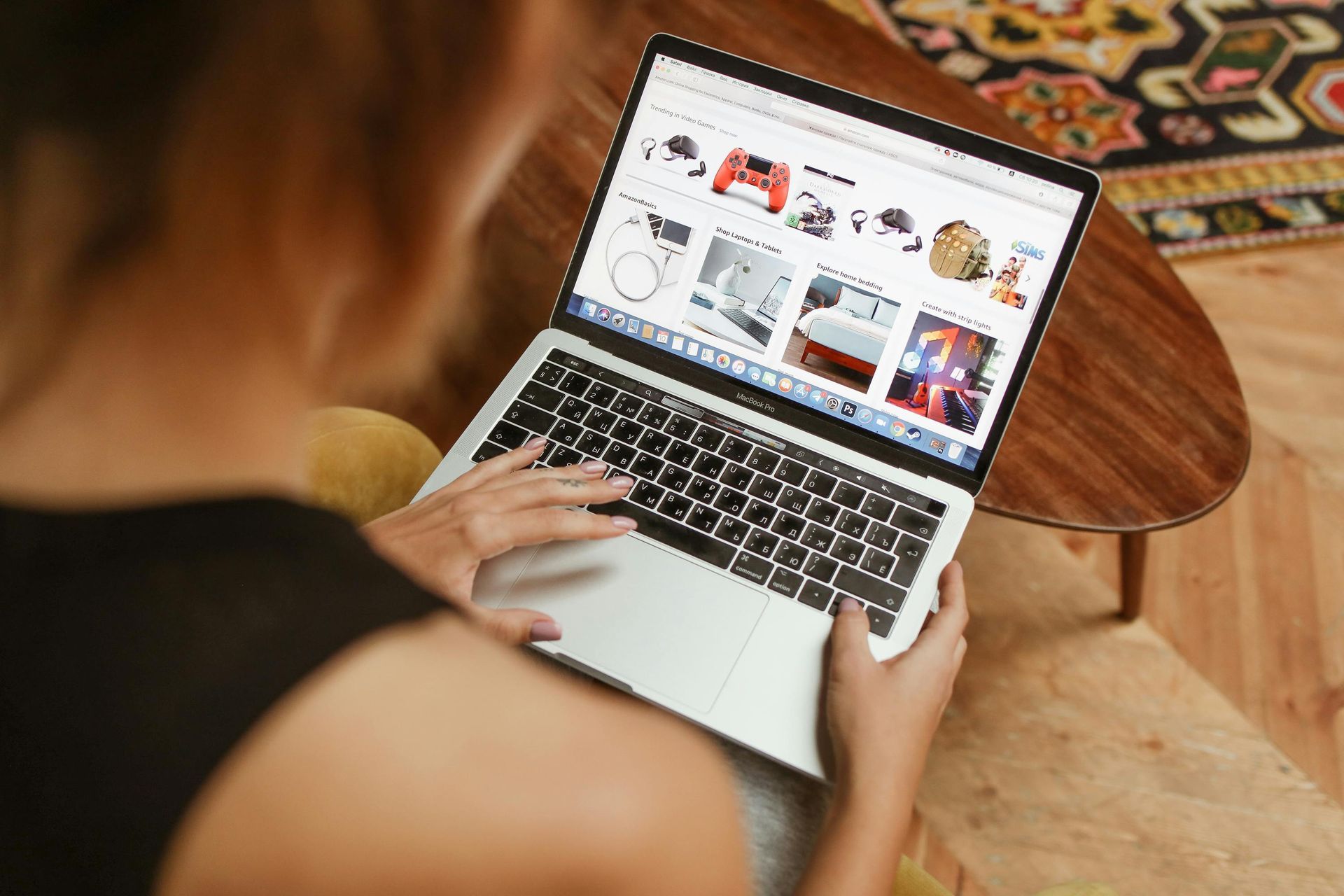 View Current Auctions A woman is sitting on a couch in front of a coffee table with a laptop, shopping a Collins & Co. Online Auction and placing online bids.