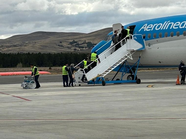 Personal del aeropuerto embarcando pasajeros en las escaleras de un avión de Aerolíneas Argentinas en la pista.