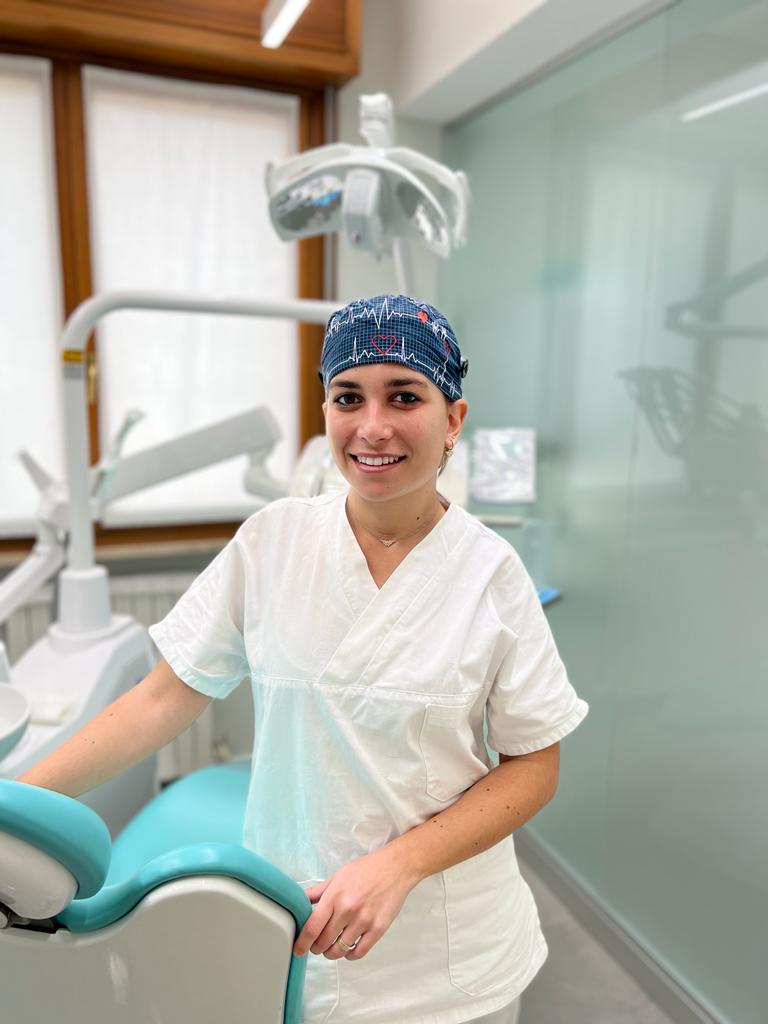 Una donna in uno studio dentistico è in piedi accanto a una poltrona del dentista.