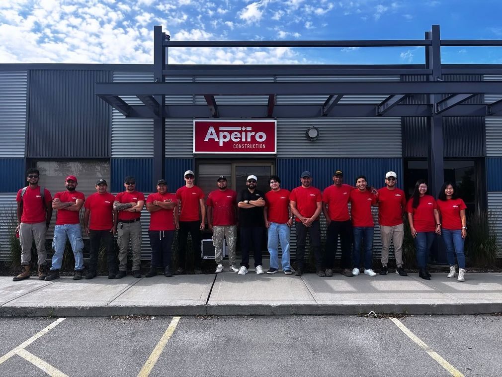Group of people in red shirts standing outside an Apeiro storefront