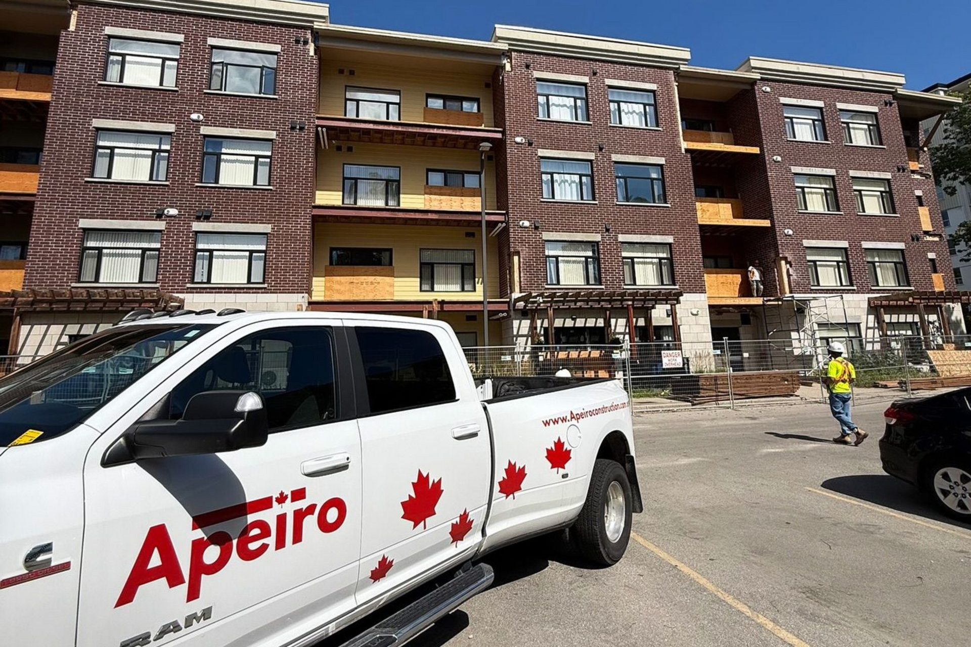 White Apeiro pickup with red maple leaves parked in front of a brick apartment building and stairwell.