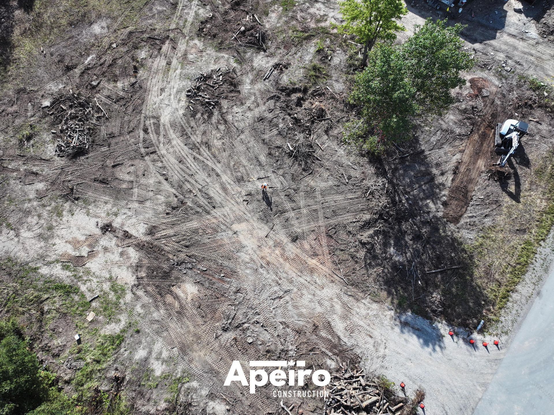 Aerial view of a rocky slope with sparse trees and a person on a path near the right edge.
