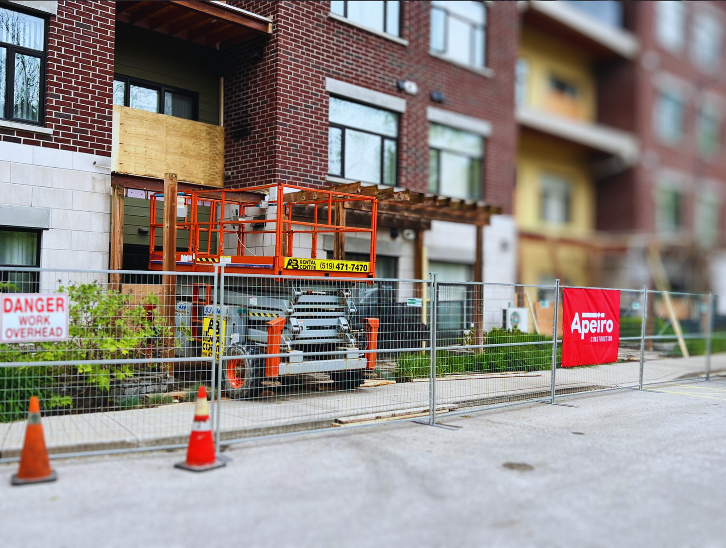 Construction site outside brick apartments with orange scaffold, cones, fencing, and an Apache truck.