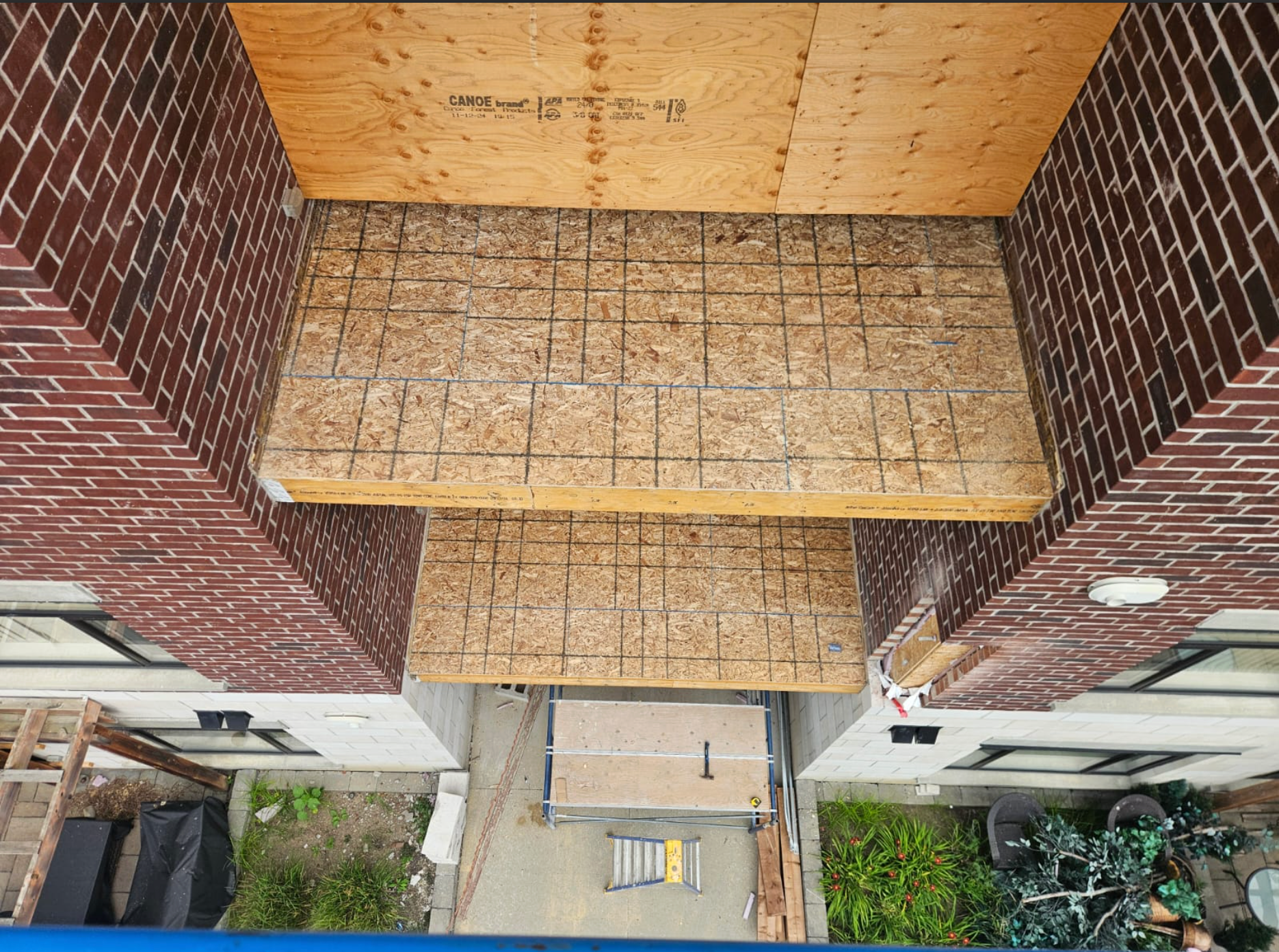 Top-down view of a brick apartment entrance with tiled steps and a walkway below