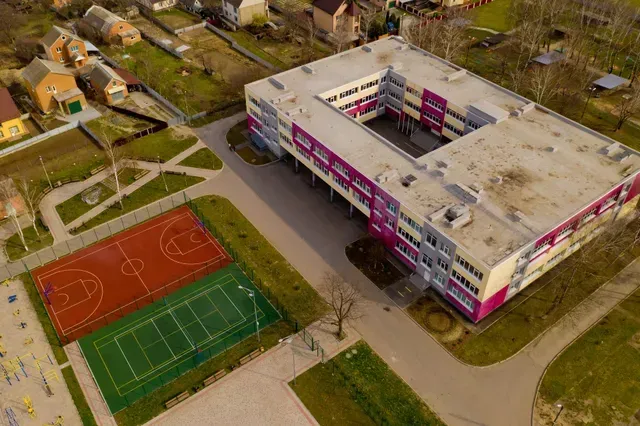 Aerial view of a school with an outdoor basketball court and soccer field