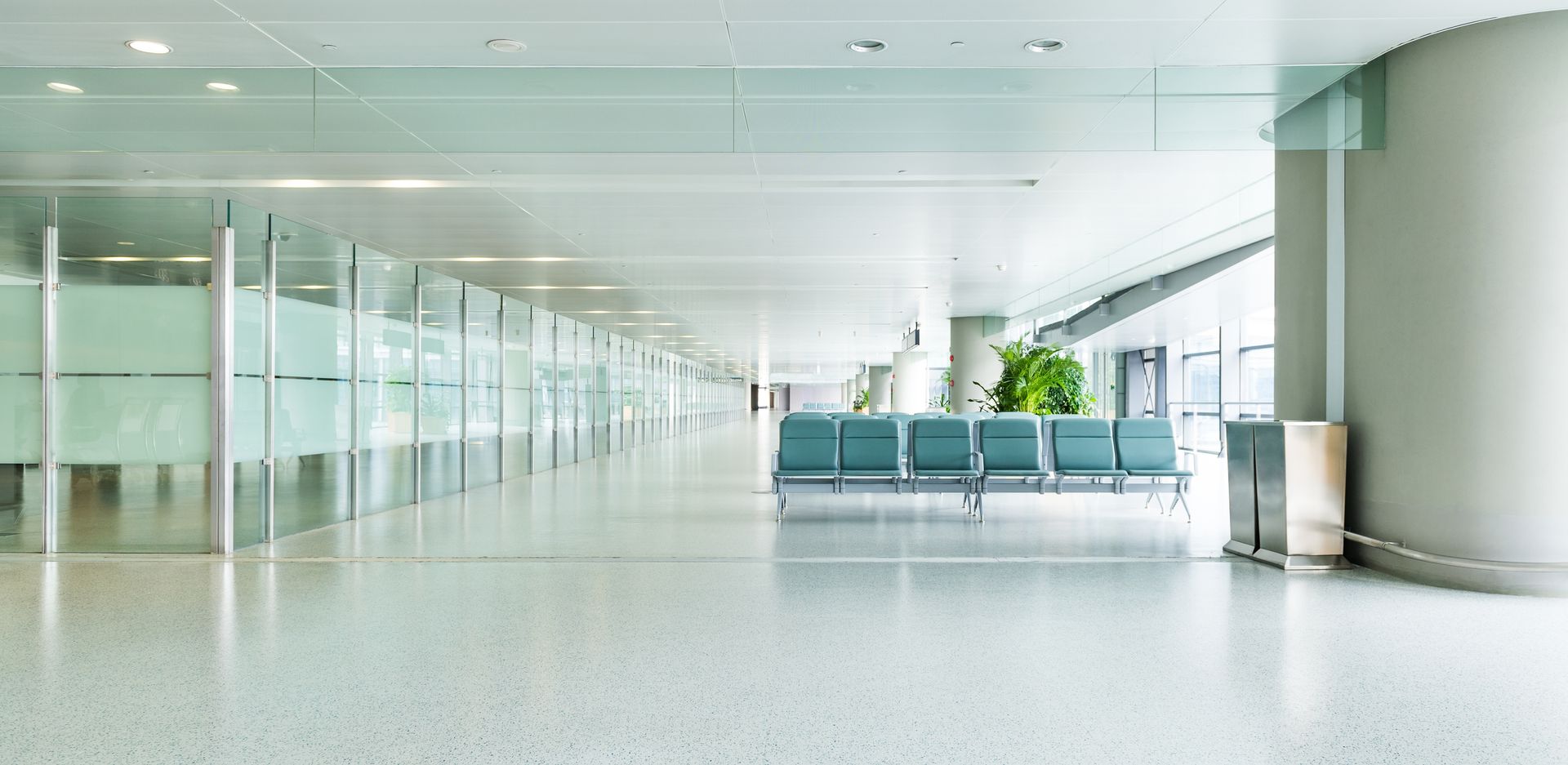 Empty modern airport terminal with glass walls, rows of seats, and a bright polished floor
